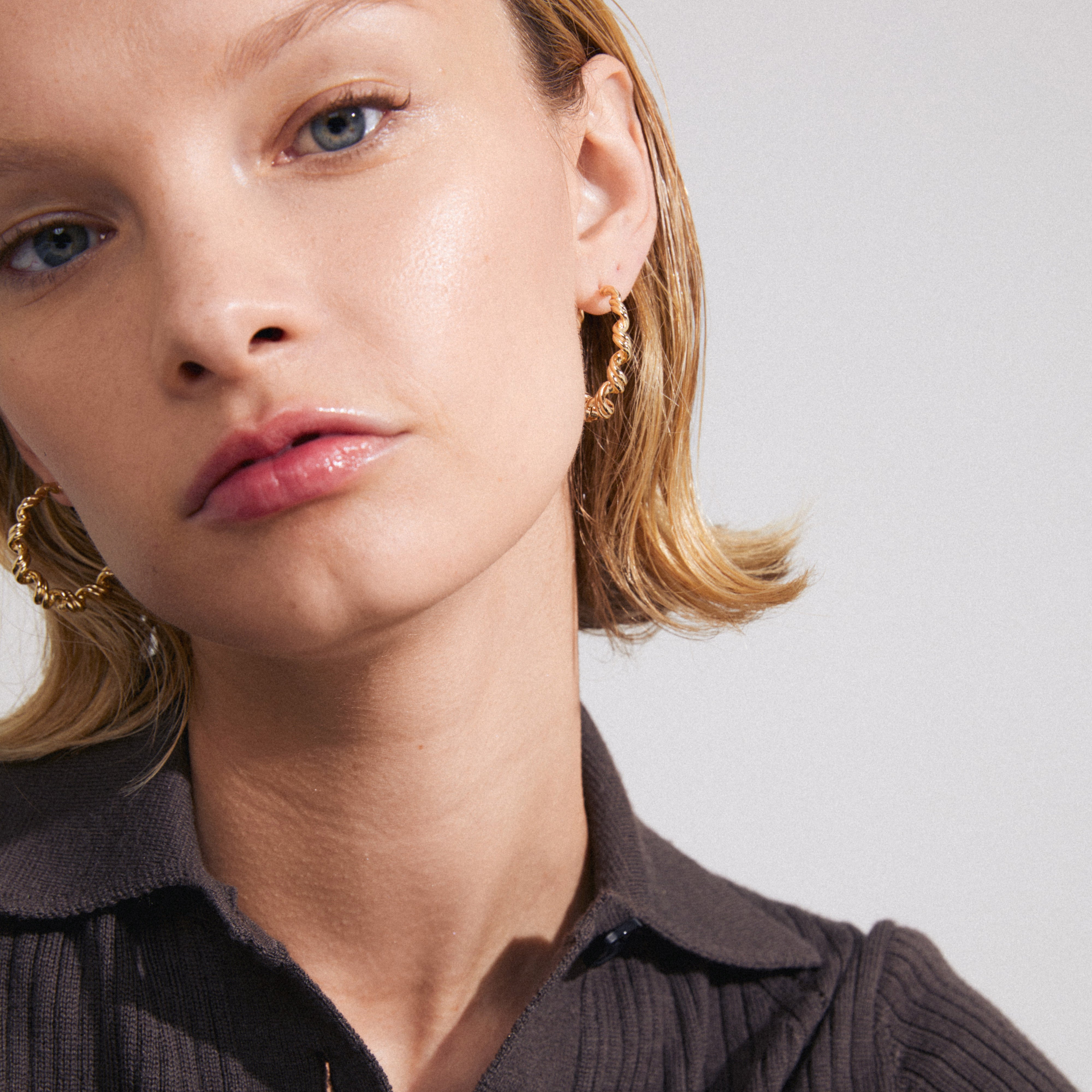 LARISA earrings gold-plated with a twisted silhouette worn by a woman, showcasing their boho-inspired, classy design, exuding warmth and style.
