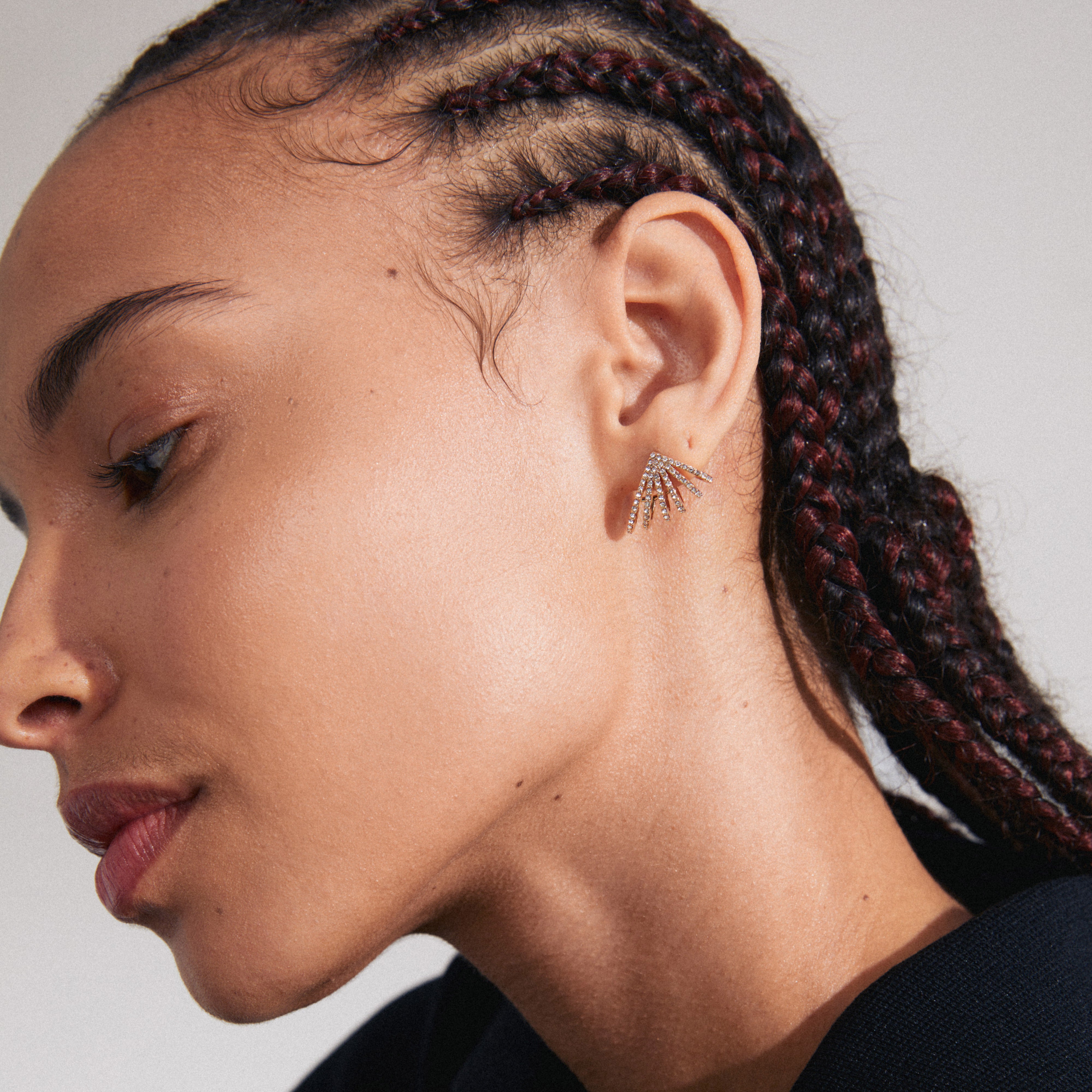 PRISCILLA earrings gold-plated, featuring shimmering Preciosa crystals in a sunray design, elegantly adorn a woman's ear, highlighting trendy, inclusive Scandinavian jewellery style.