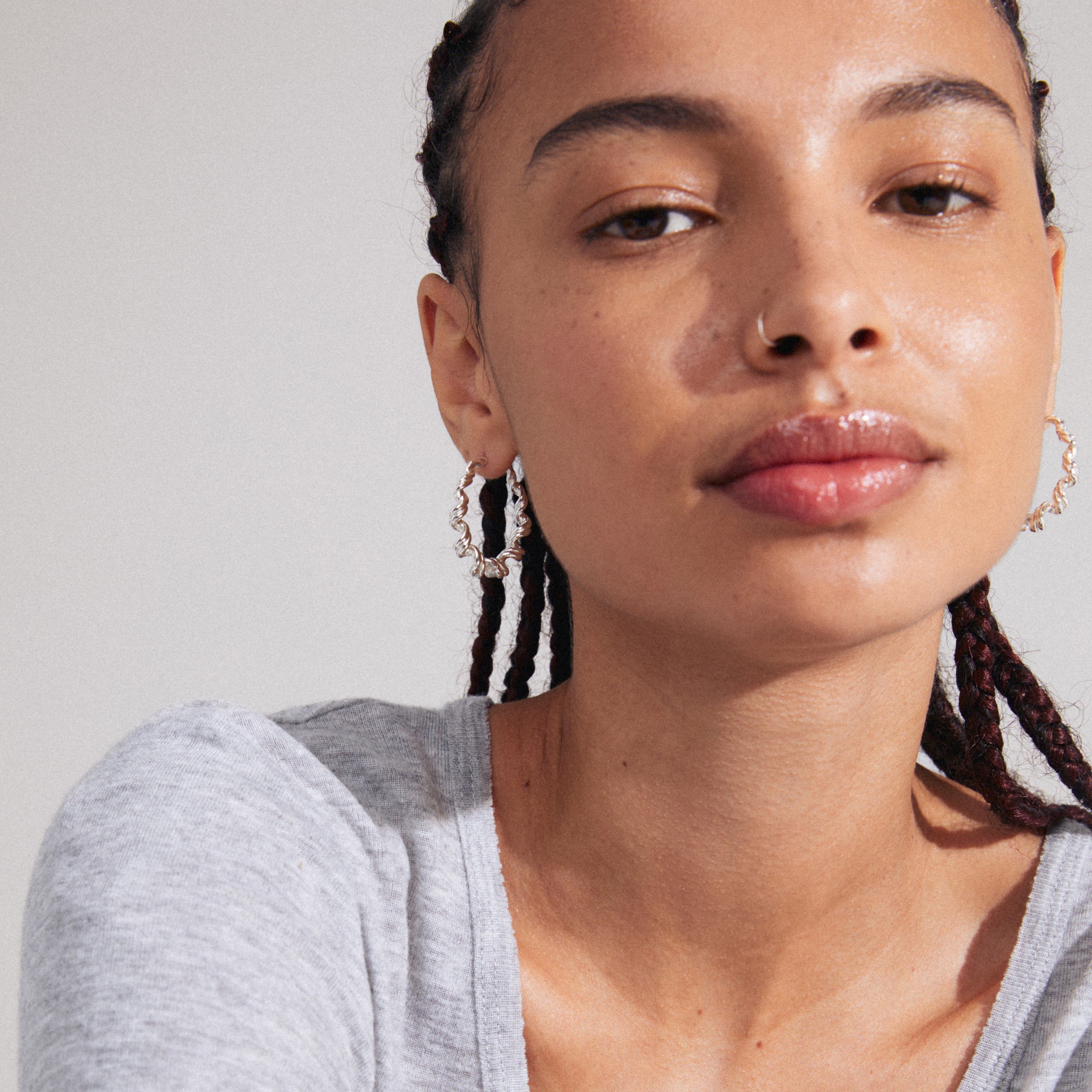 LARISA silver-plated earrings featuring twisted hoops worn by a woman with braids, capturing Pilgrim’s boho-inspired style and sustainable craftsmanship.