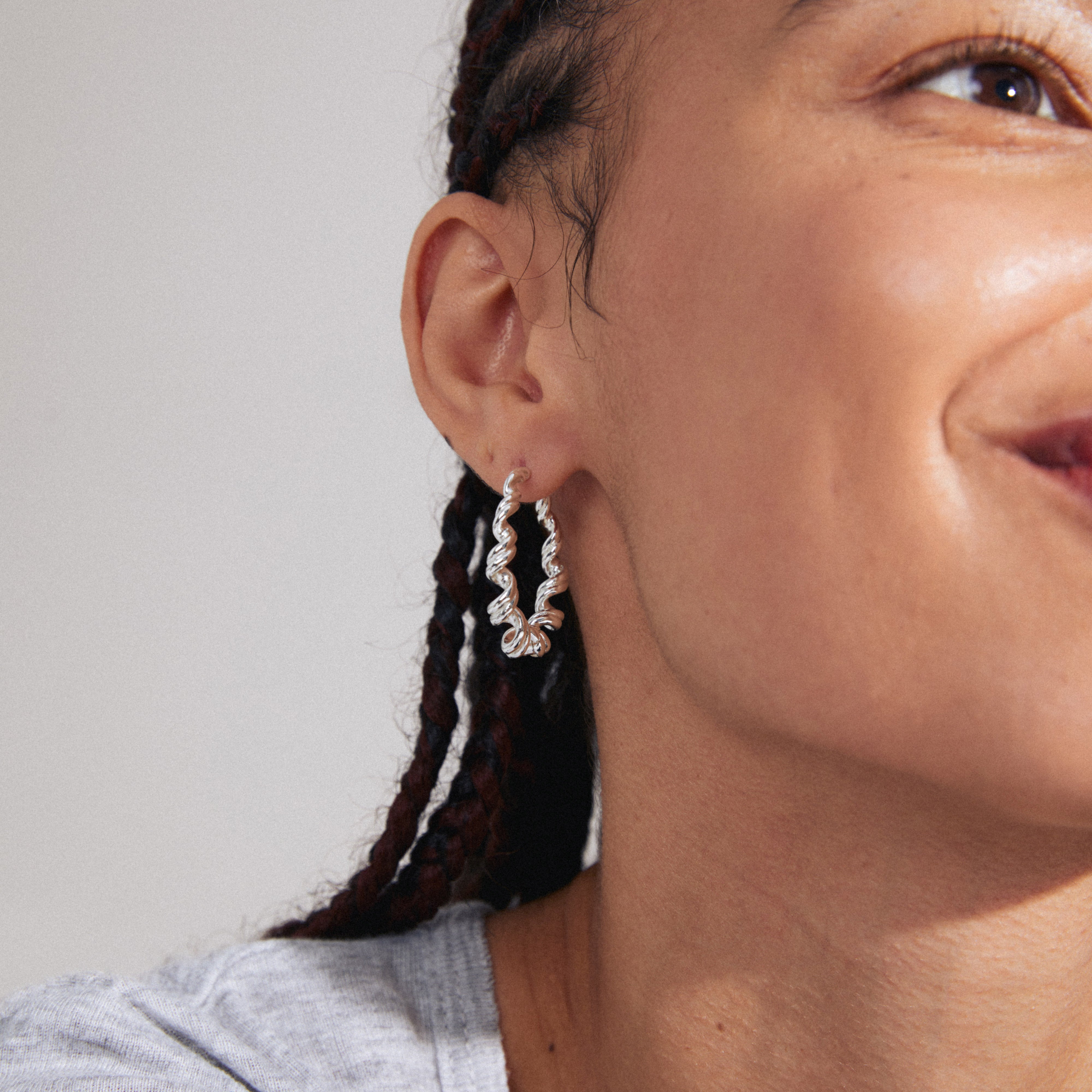 LARISA earrings silver-plated, featuring twisted hoops with a boho vibe, worn by a woman. Eye-catching, sustainable design from Pilgrim's handmade Danish jewelry collection.