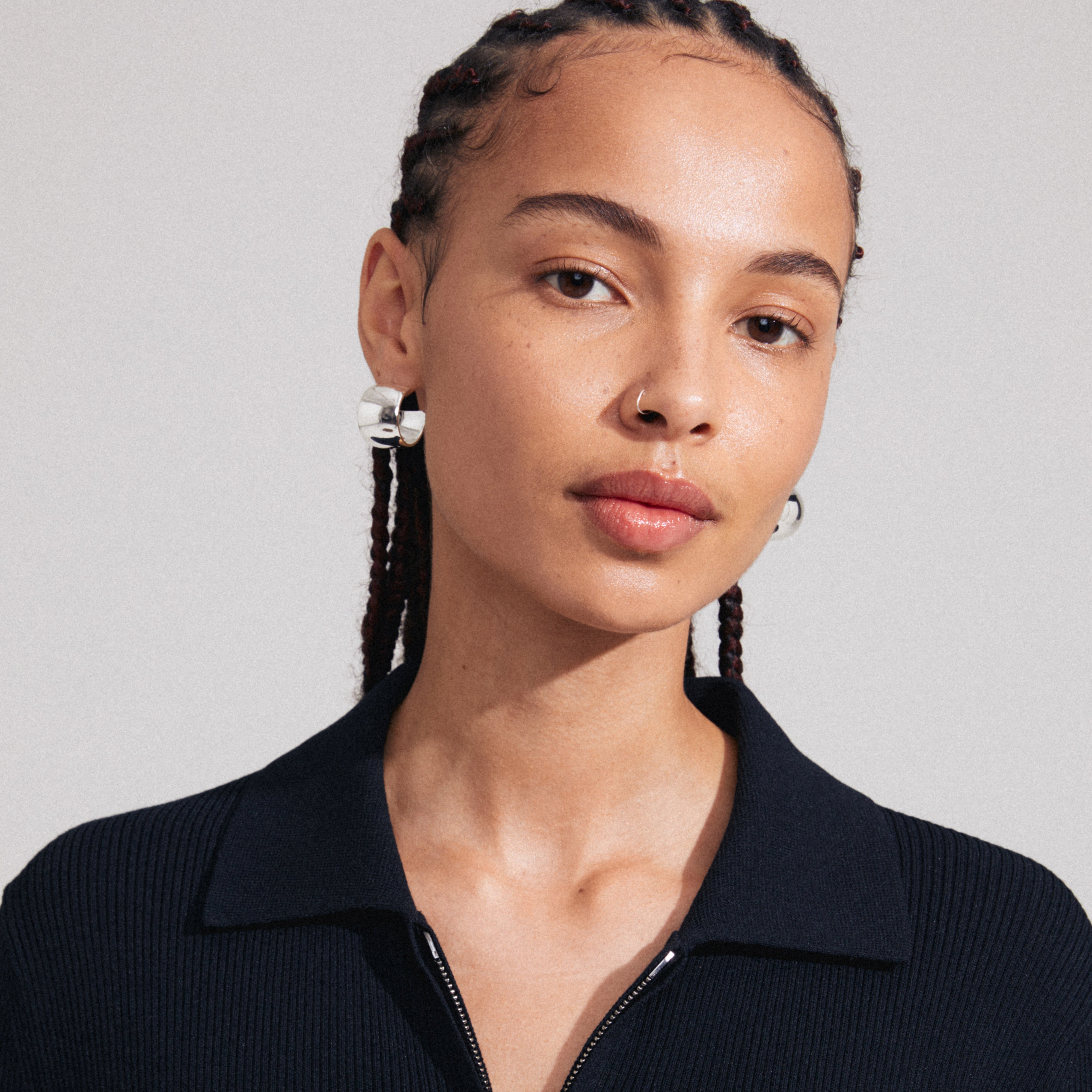 Woman wearing TALULLA silver-plated earrings, showcasing their ultra-wide, glossy shine; perfect for a trendy, sustainable fashion statement.