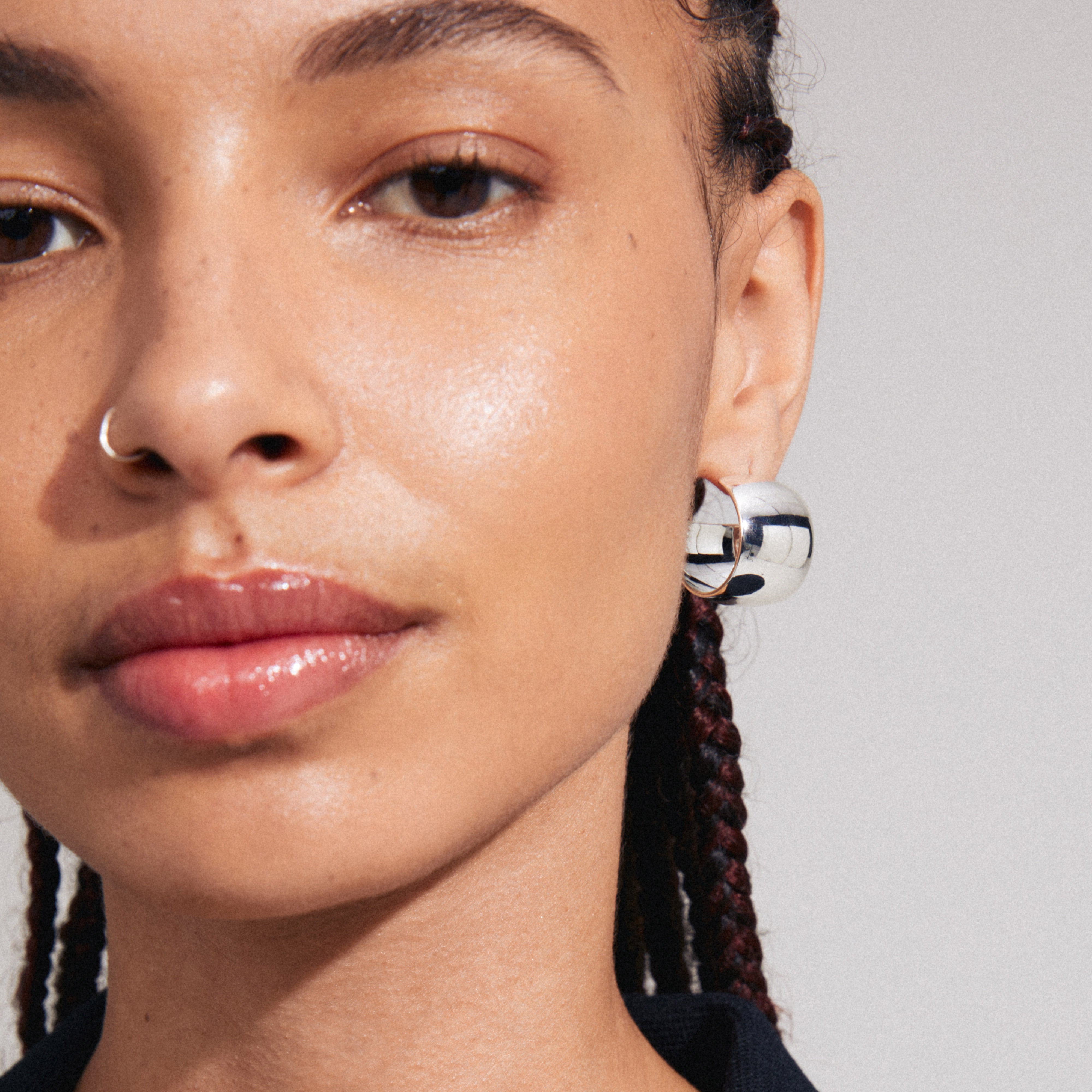 TALULLA earrings: Silver-plated, ultra-wide hoops with a glossy finish, worn by a woman with a nose ring, embodying trendy, recycled Danish design.