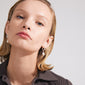Close-up of a woman wearing the CONSTANCE earrings 2-in-1 set, featuring silver-plated hoops with freshwater pearl and glasspearl studs from Pilgrim.