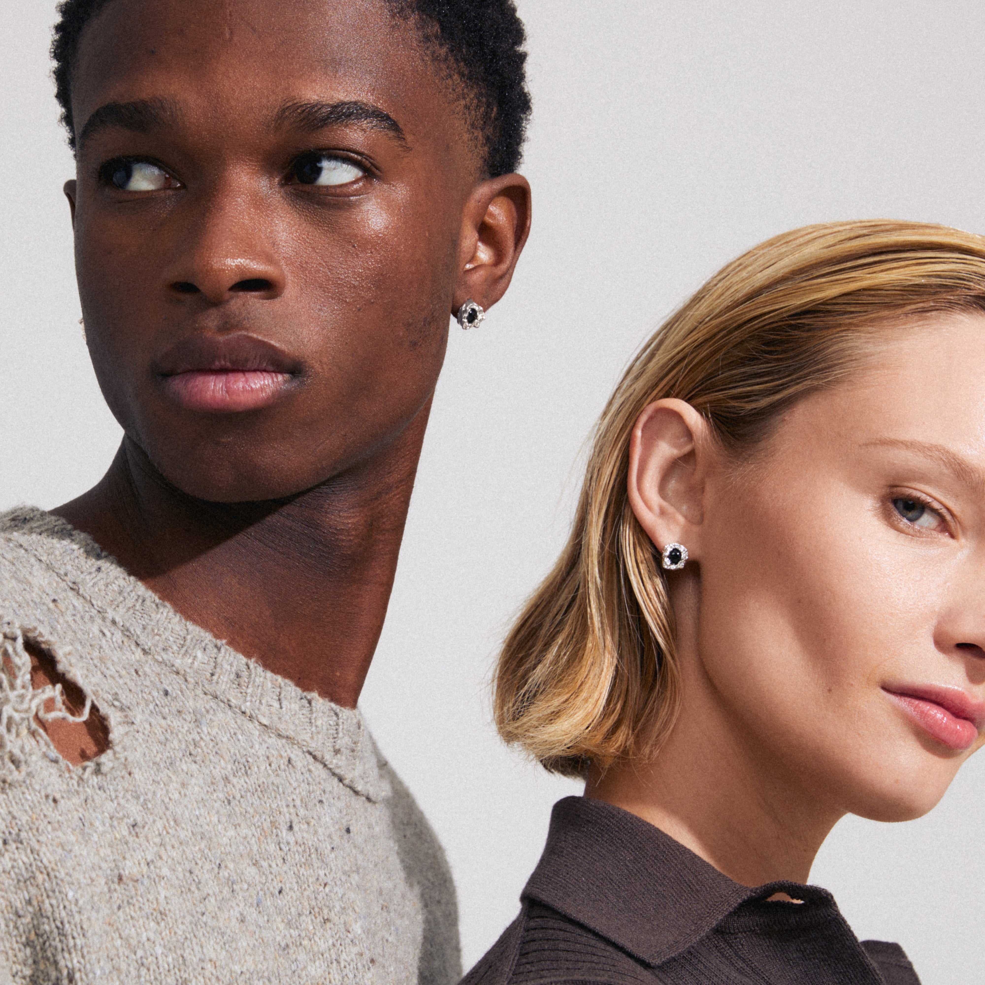 Man and woman wearing Pilgrim's RYPER silver-plated earrings, showcasing sleek black Agate stones, highlighting minimalist design and elegance.