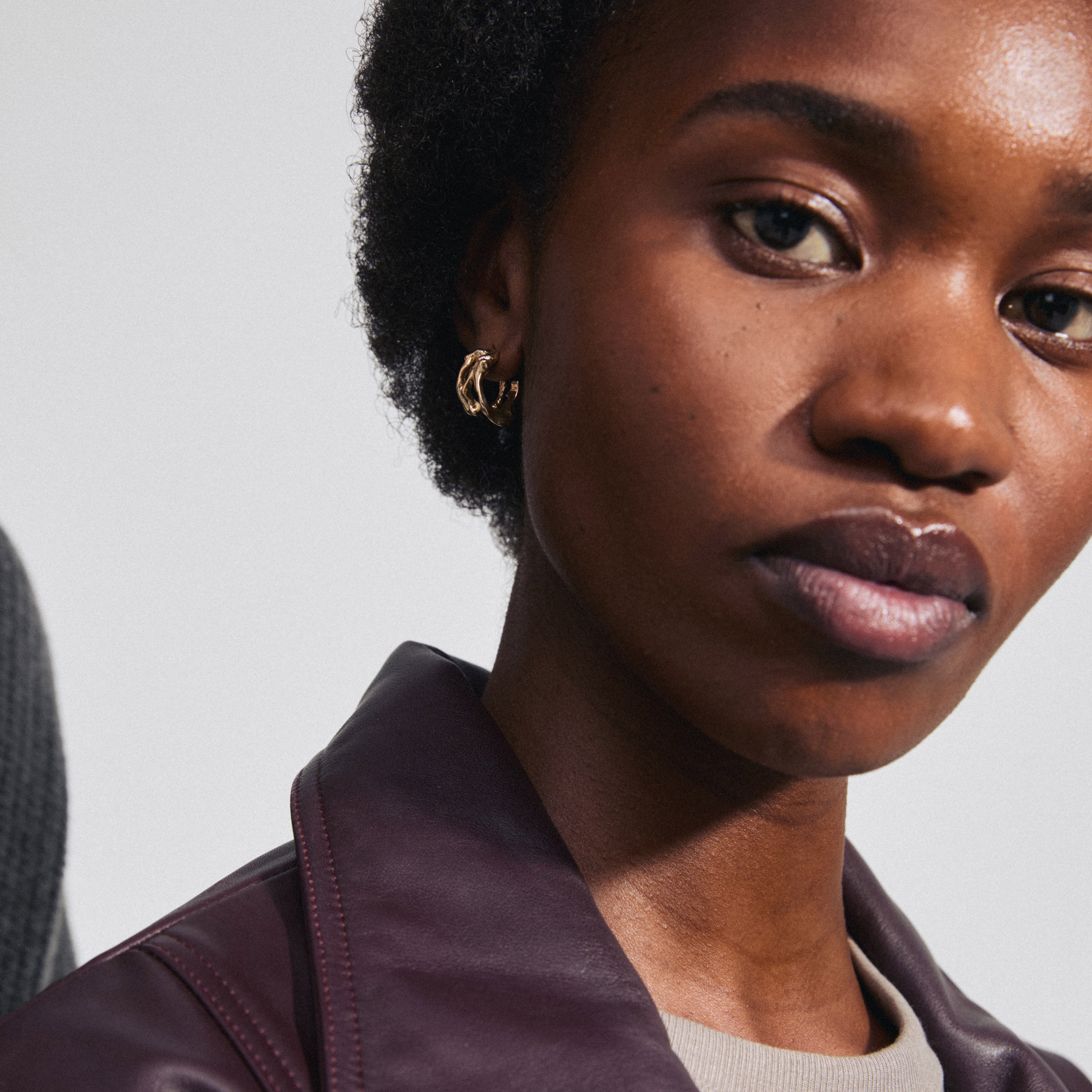 FOTINI gold-plated hoop earrings showcased on a woman wearing a purple jacket, highlighting their organic, lightweight design and effortless elegance.