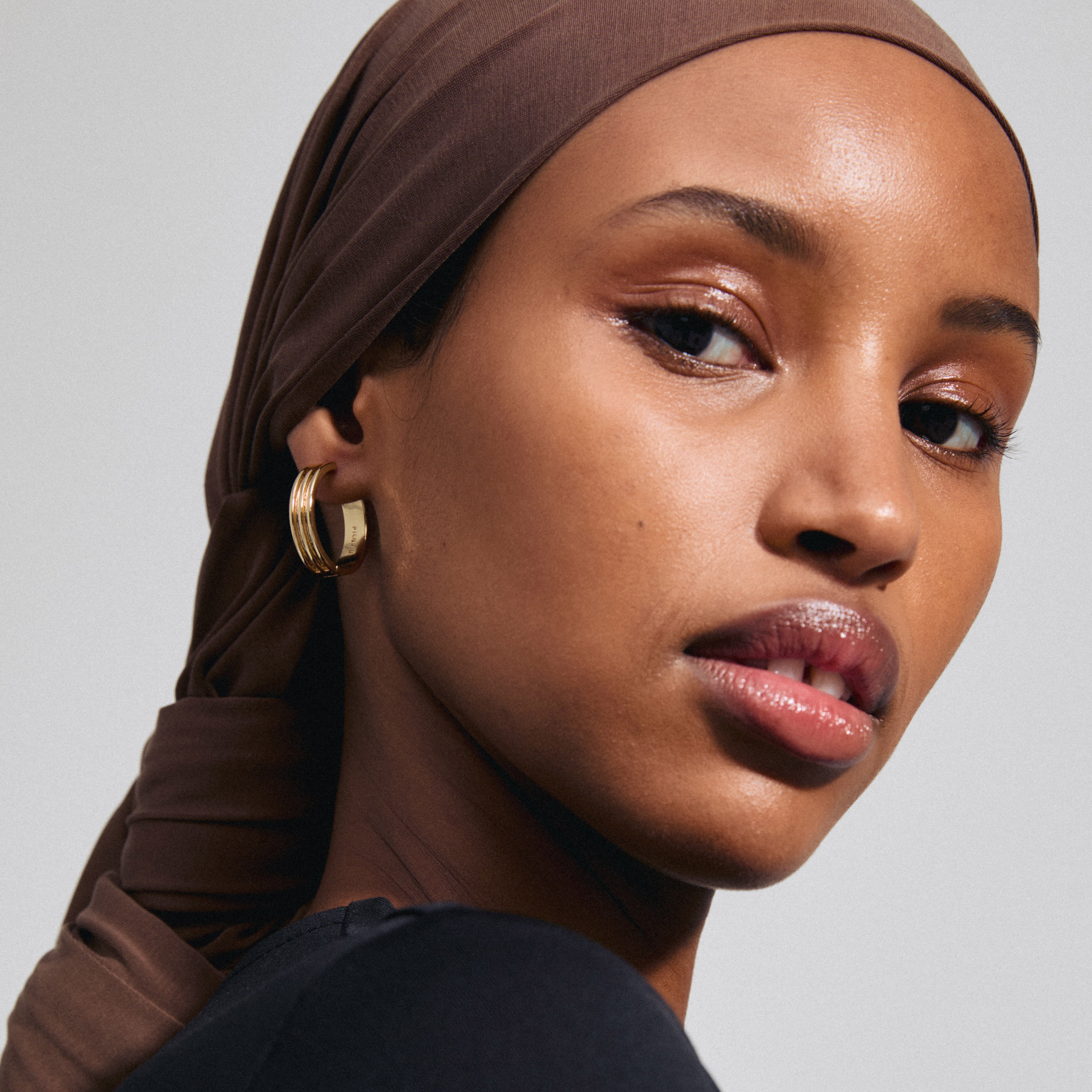 Close-up of a woman wearing BENNETT gold-plated hoop earrings from Pilgrim, showcasing their classic, minimalist design and easy-to-use clasp.
