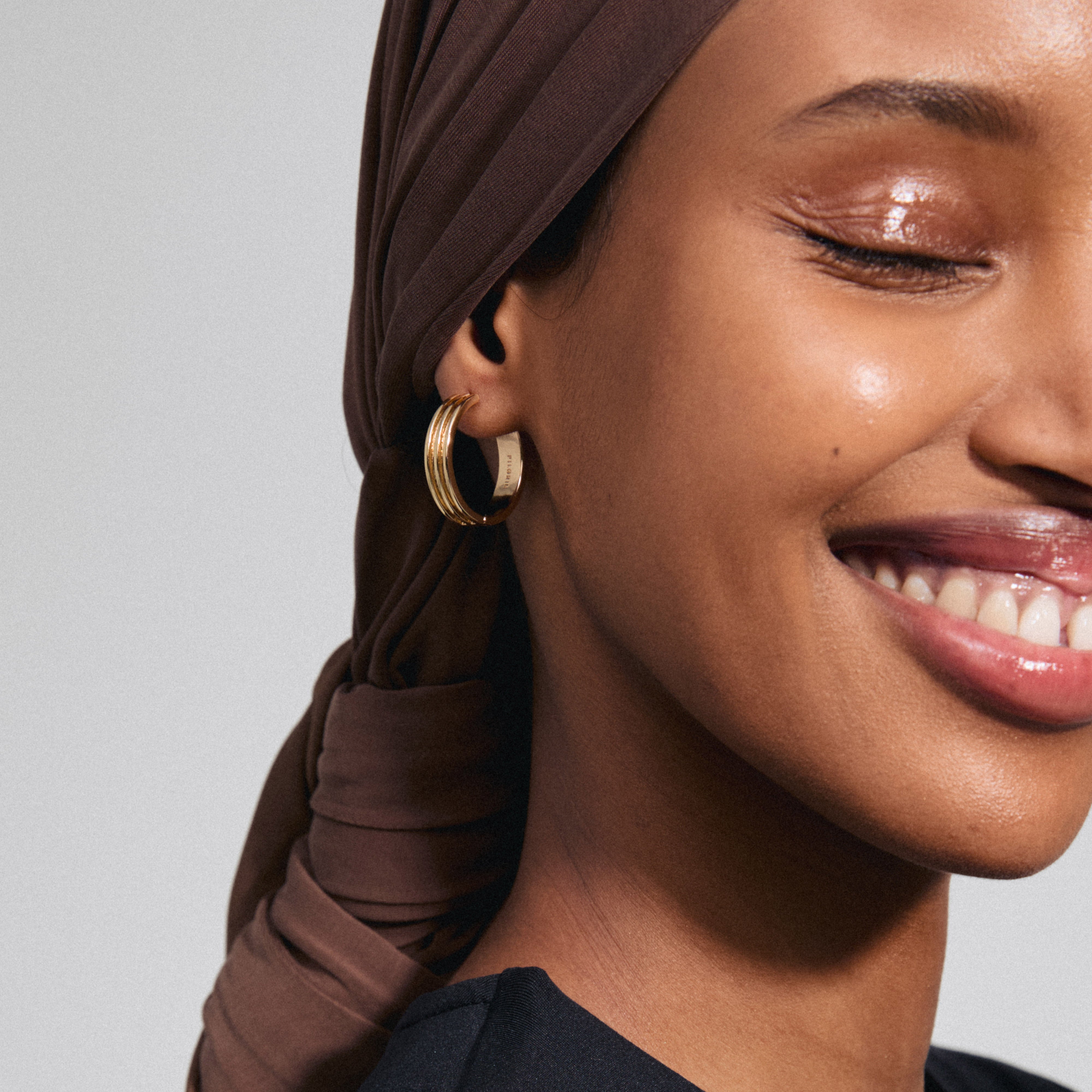 Close-up of a woman wearing BENNETT gold-plated hoop earrings from Pilgrim, showcasing their classic, minimalist design with a modern touch.