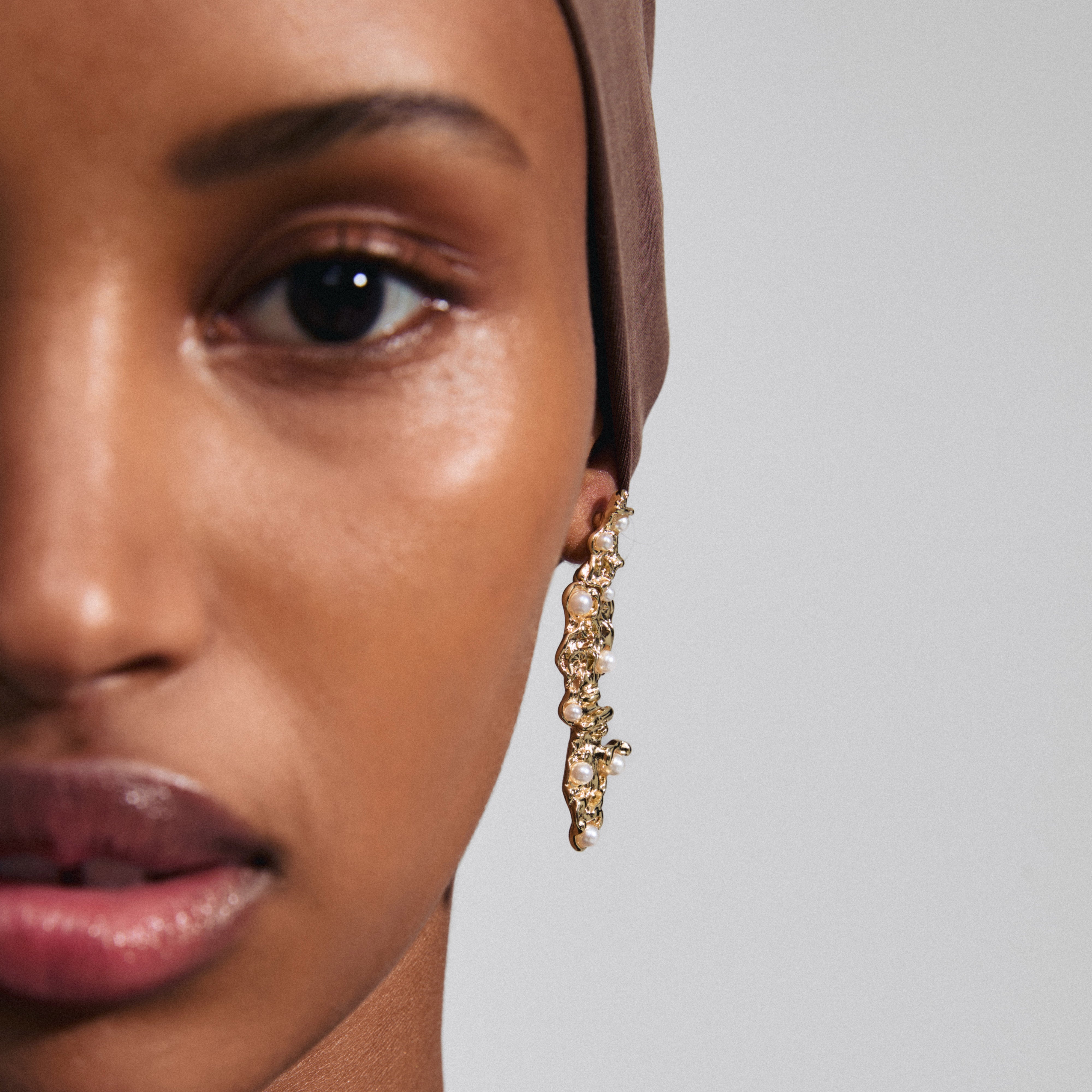 JUDE earrings gold-plated, featuring an organic design with pearlescent beads, worn by a woman. Perfect for a powerful, stylish look.