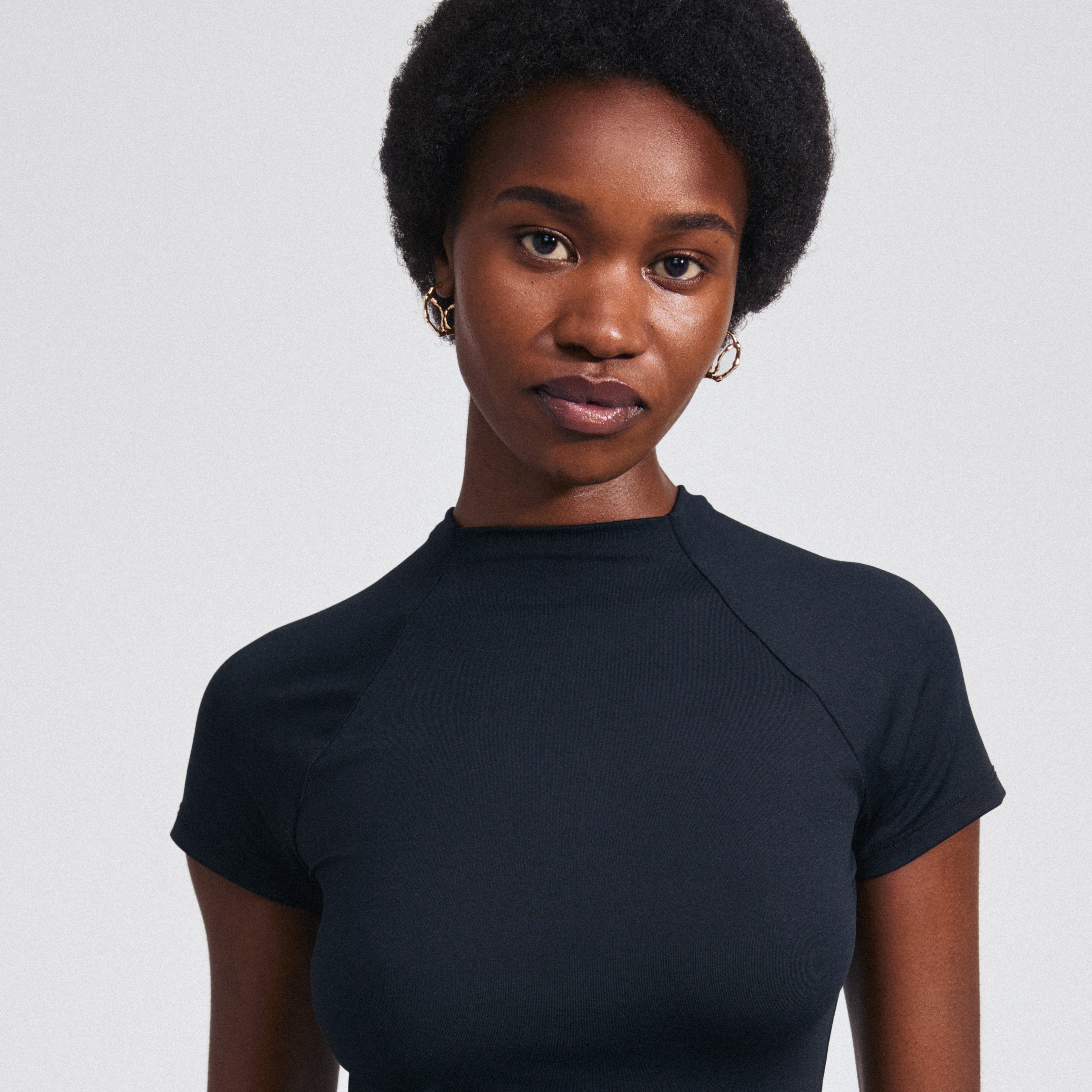 Woman wearing DIDO gold-plated hoop earrings, showcasing their organic design and unique modern twist, highlighting Pilgrim's emphasis on style and sustainability.