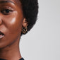 Close-up of a woman's face showcasing Pilgrim's DIDO gold-plated hoop earrings, emphasizing their organic design and modern twist on classic hoops.