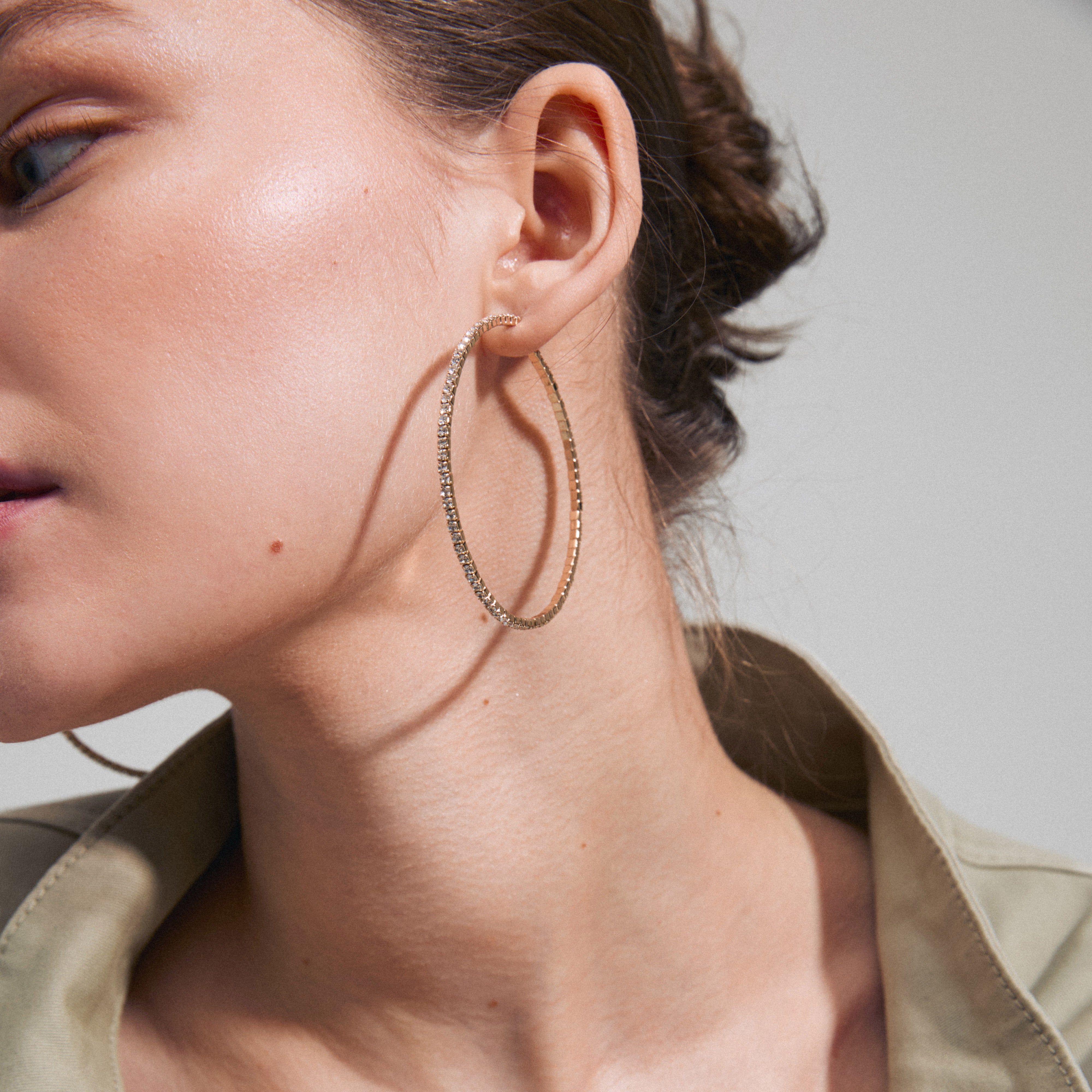 SIDNEY crystal hoop earrings, gold-plated, featuring sparkling Preciosa crystals worn by a woman, embodying elegance and confidence for a glamorous night out.