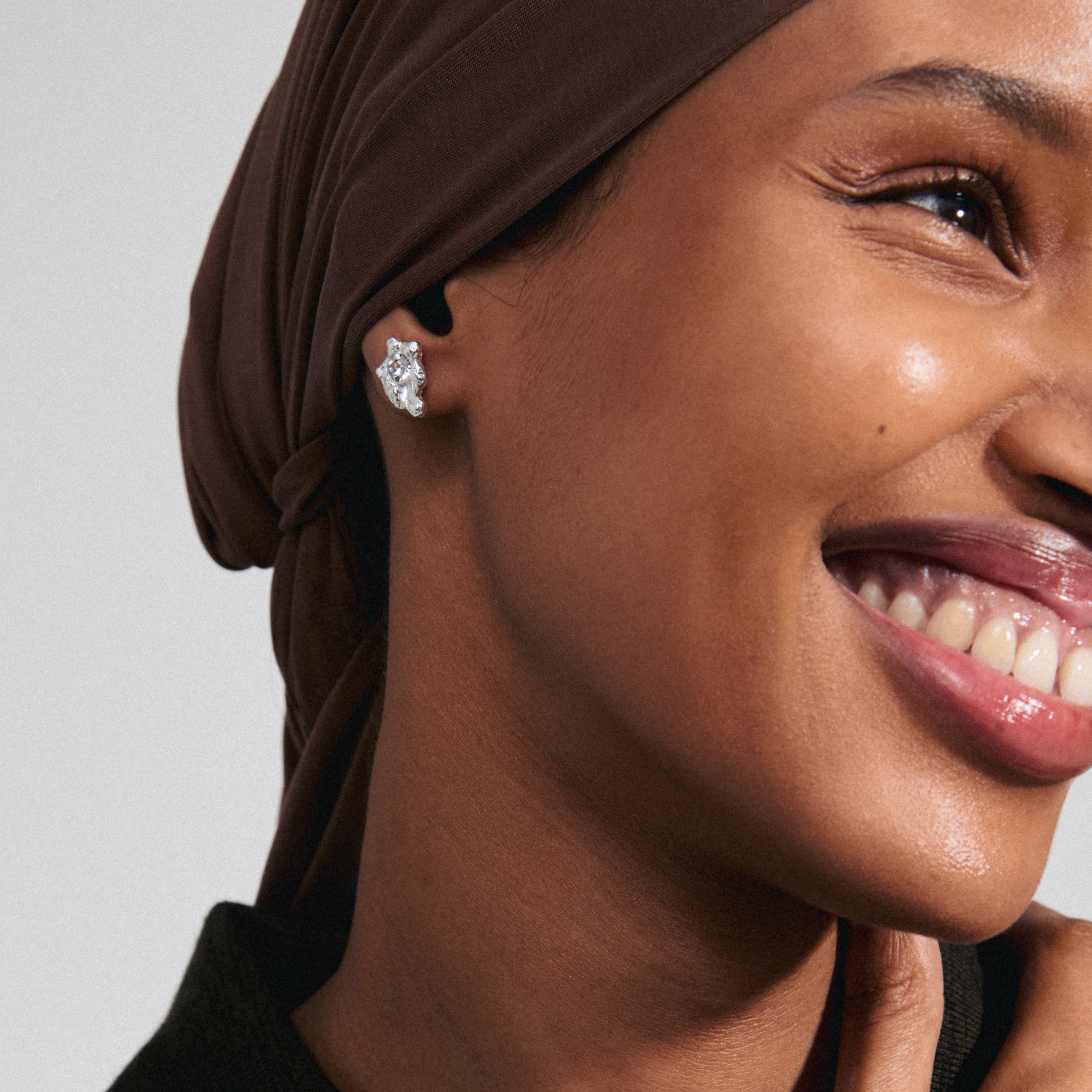 Woman wearing AIAS crystal earrings, silver-plated, showcasing sparkling Preciosa crystals in an organic design, reflecting Pilgrim's timeless Danish craftsmanship and modern elegance.