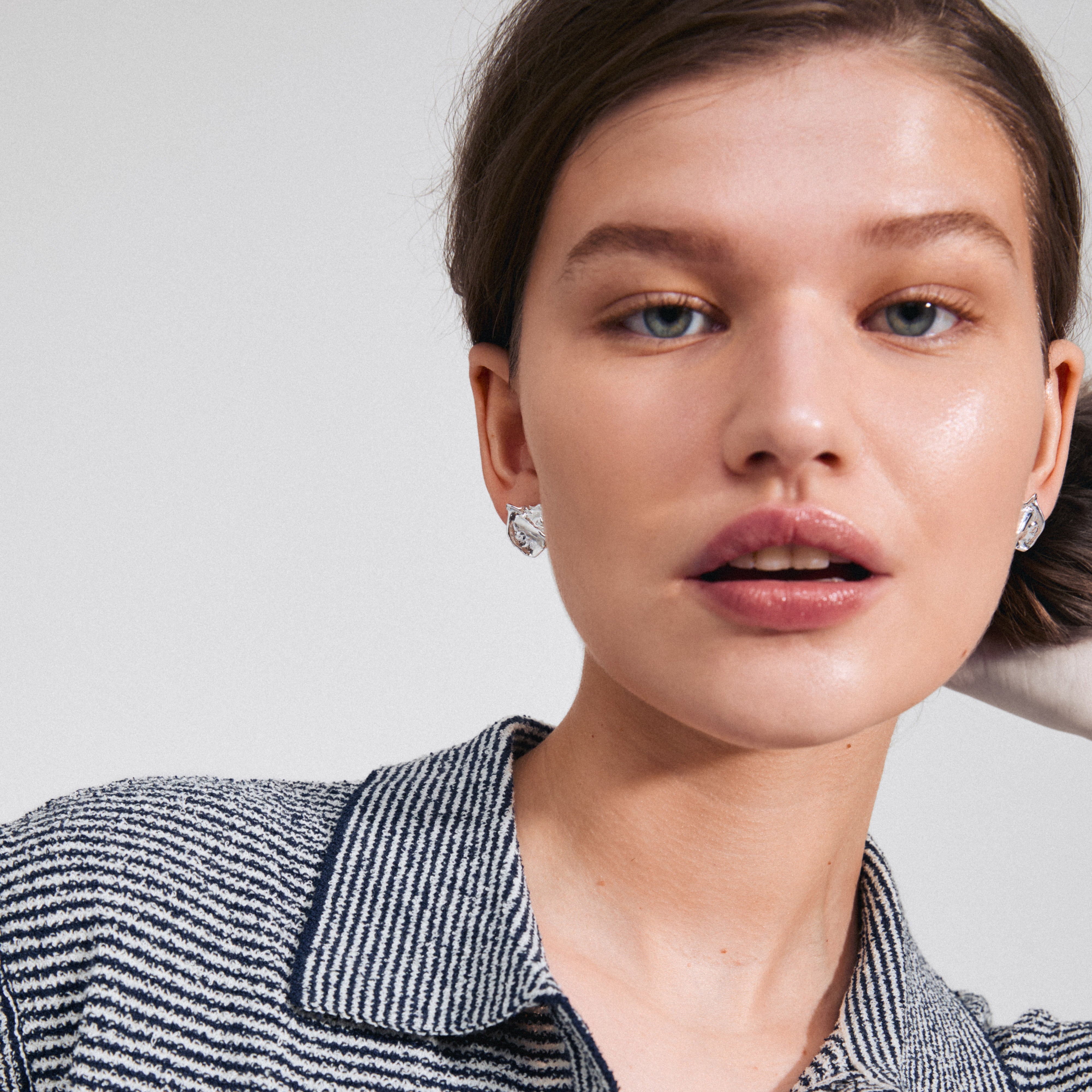 Close-up of a woman wearing LAVENDER silver-plated stud earrings from Pilgrim, showcasing their organic design and handcrafted elegance.