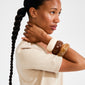 Young woman wears the AASE maxi bangle beige by Pilgrim, a chunky recycled acrylic bracelet stacked with two others, showcasing a minimalist Scandi style.