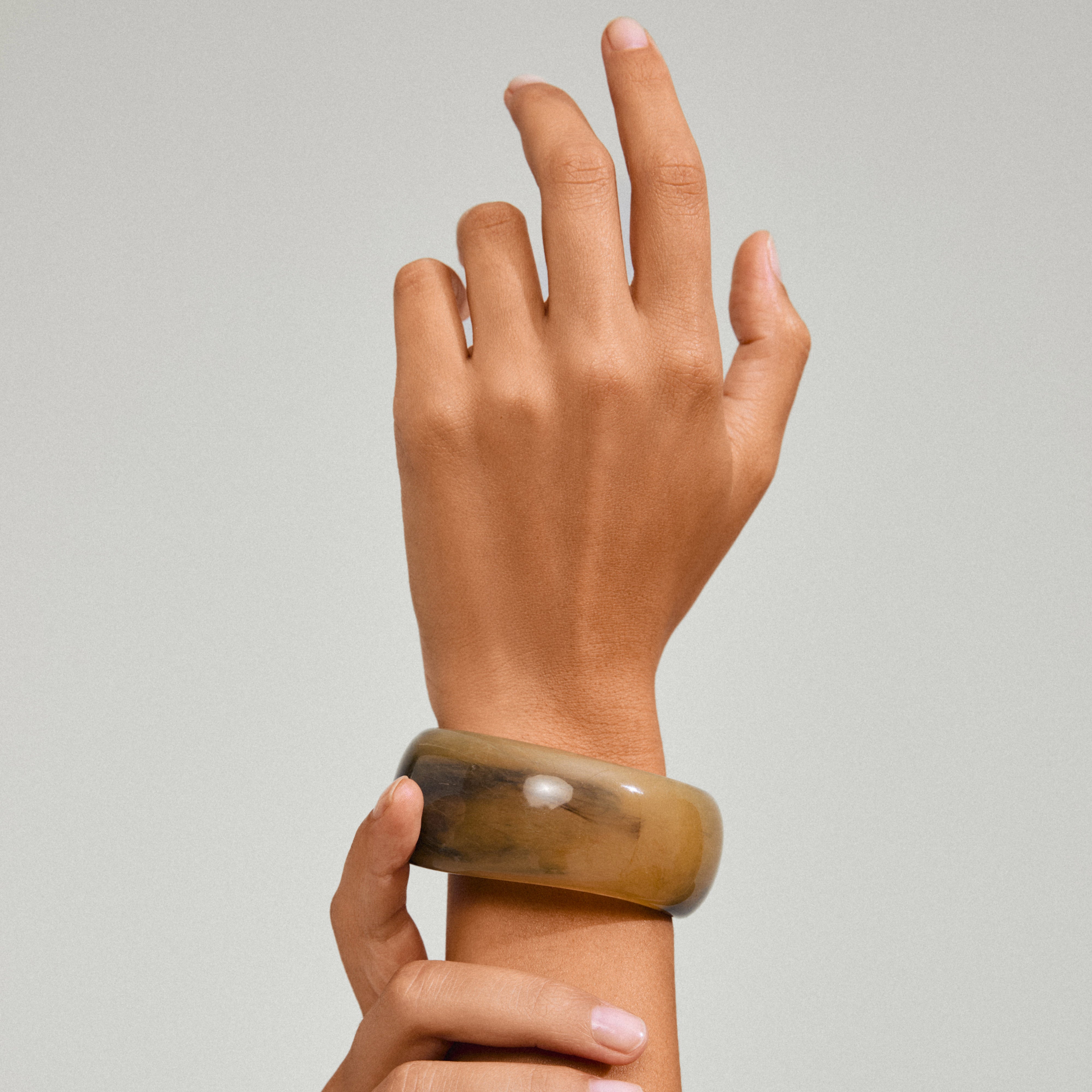 AASE maxi bangle green on hand, showcasing its chunky, marbled texture, embodying Pilgrim's trendy, minimalist Scandinavian style.