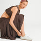 Young woman adjusts the JOANNA gold-plated anklet from Pilgrim, showcasing its sleek, herringbone design paired with a relaxed, minimalist outfit and white sneakers.