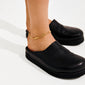 Person's lower legs wearing ARIF gold-plated anklet with organic, elongated links, paired with black leather mules. A stylish summer accessory from Pilgrim.
