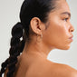 Close-up of a woman's ear wearing Pilgrim's ARTEMIS gold-plated earrings, showcasing their classic Scandinavian-inspired hoop design and shiny finish.