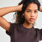 Close-up of a woman wearing APPOLLONIA gold-plated earrings, showcasing beaded hoops ideal for a relaxed summer style.