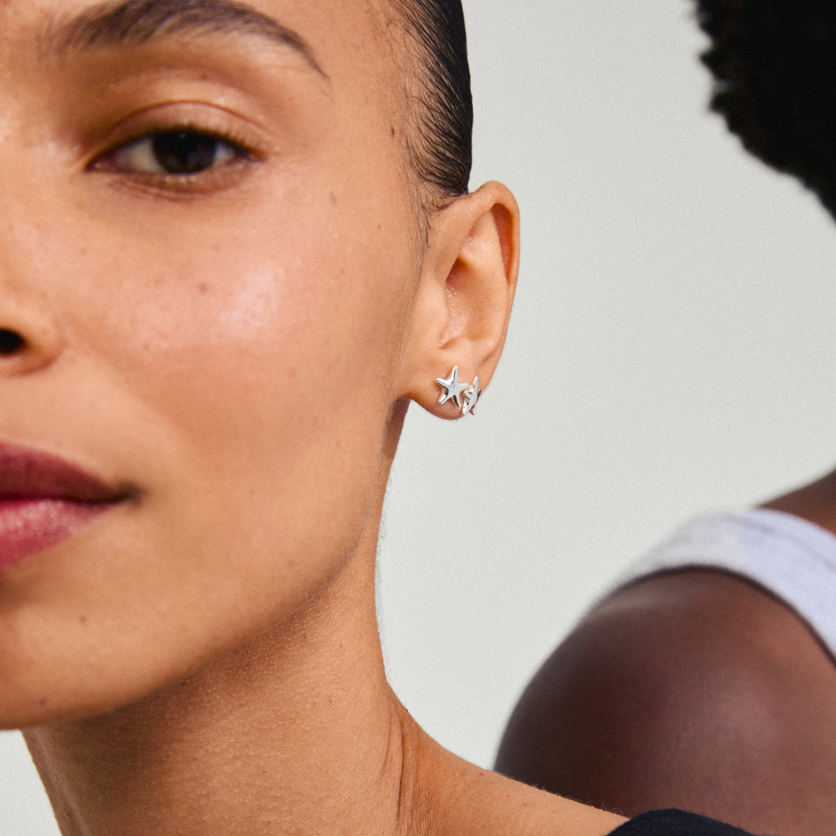 Silver-plated ANDRÉ starfish stud earrings on a woman's ear, embodying beach-inspired summer vibes, crafted from recycled materials by Pilgrim.