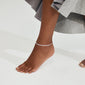 Close-up of a foot wearing the JOANNA silver-plated anklet, a sleek herringbone chain, ideal for enhancing summer style with a touch of elegance.