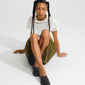 Young person wearing a silver-plated JOANNA anklet, styled with minimalist black slip-ons and an olive skirt, highlighting its elegant, light-reflecting herringbone chain design.