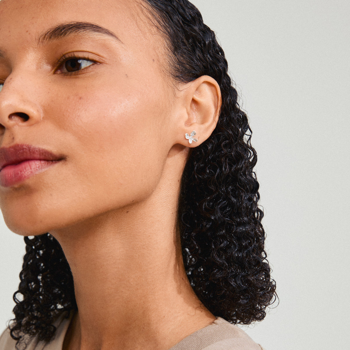 AGLAIA earrings silver-plated, featuring a delicate floral design, adorn a woman’s ear, highlighting Pilgrim's artistic essence and eco-friendly craftsmanship.