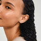 Close-up of a woman's ear showcasing Pilgrim's silver-plated ARCHER earrings with sparkling crystals and turtle design, symbolizing nature's beauty.