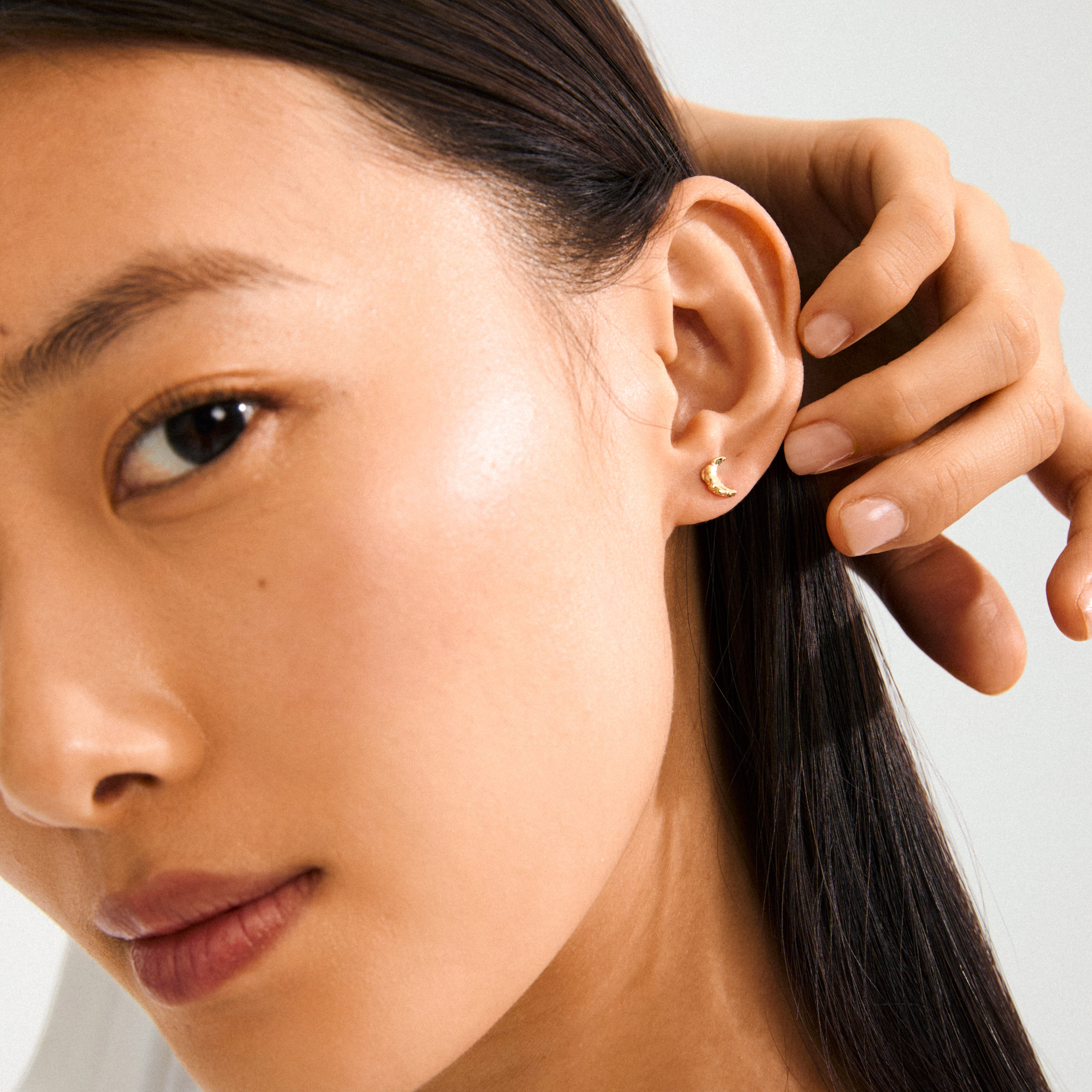 Gold-plated moon earrings from Pilgrim, featuring small rustic crescents, symbolizing new beginnings. Ideal for adding a magical touch to any outfit.