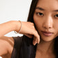 Woman showcasing the ARASH pearl bracelet, gold-plated with pearl-coloured beads, highlighting its sleek design and stylish, comfortable fit.