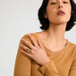 Young person wearing a camel-brown top showcases the ADRIEL ring, a chunky, gold-plated piece with fluid shapes, embodying creative energy and bold style.