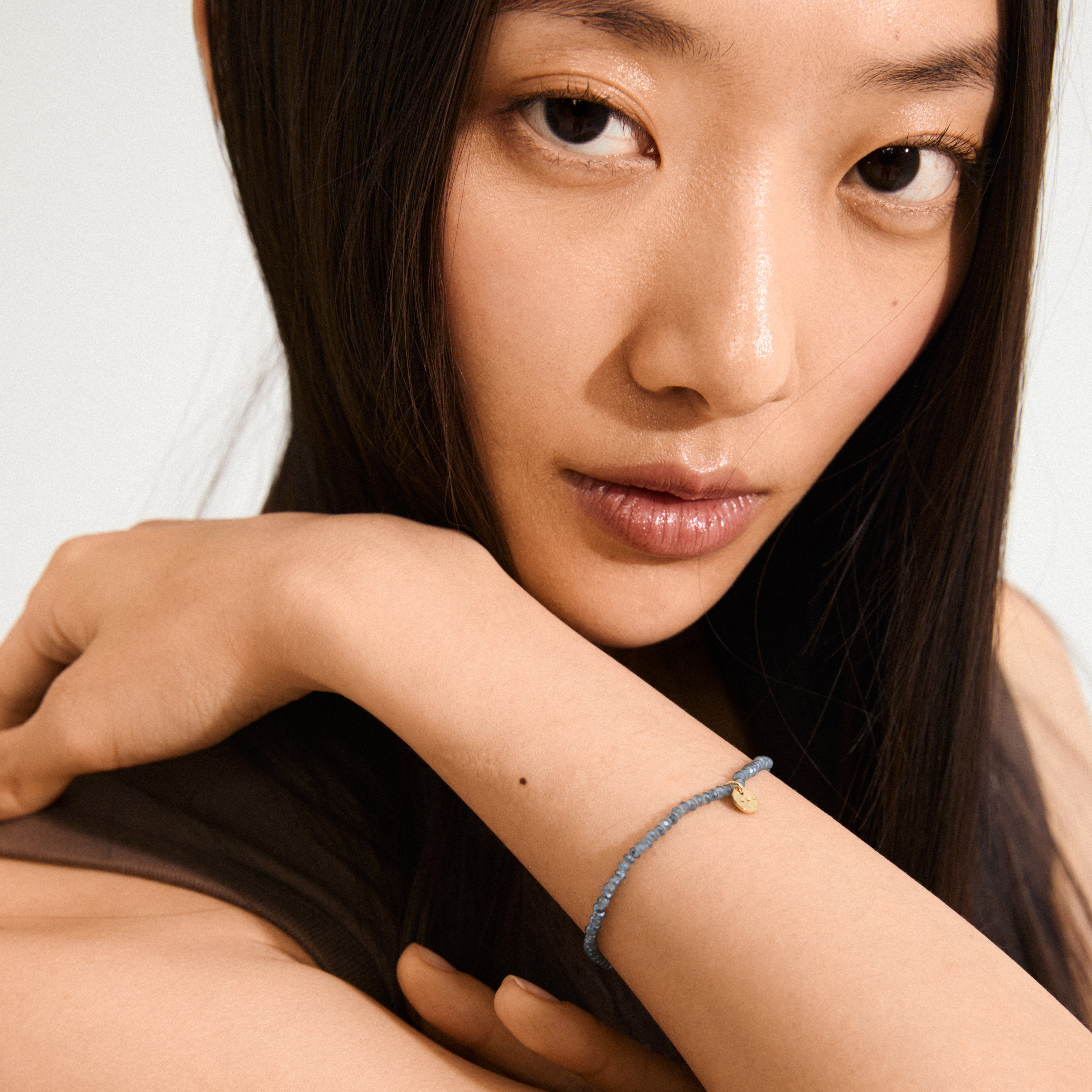 Close-up of a woman wearing the INDIE bracelet in dusty blue with gold-plated details, showcasing Pilgrim's trendy and timeless design.
