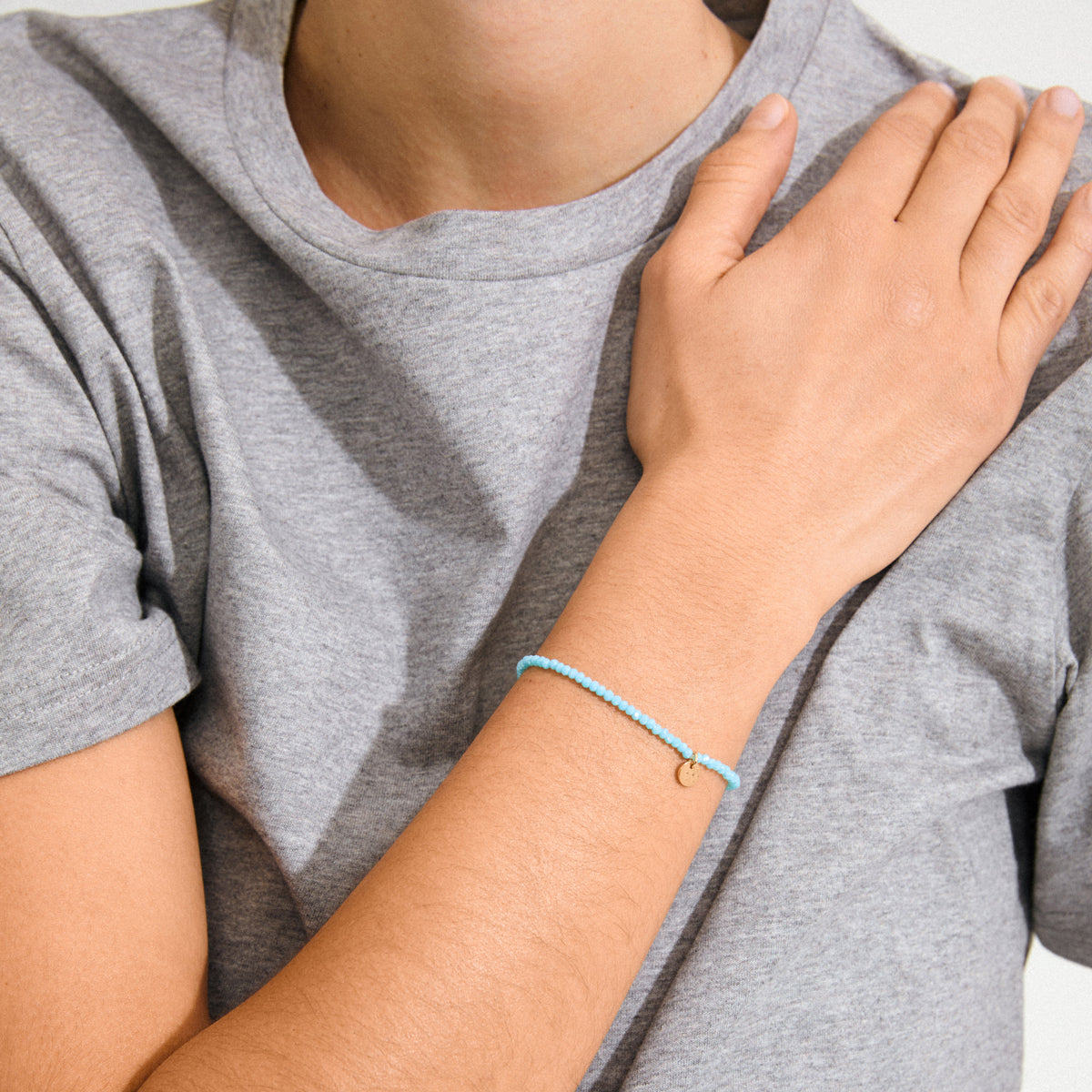 Person wearing the INDIE bracelet in sky blue and gold-plated design, featuring faceted glass beads, showcasing its stylish and versatile appeal for any occasion.