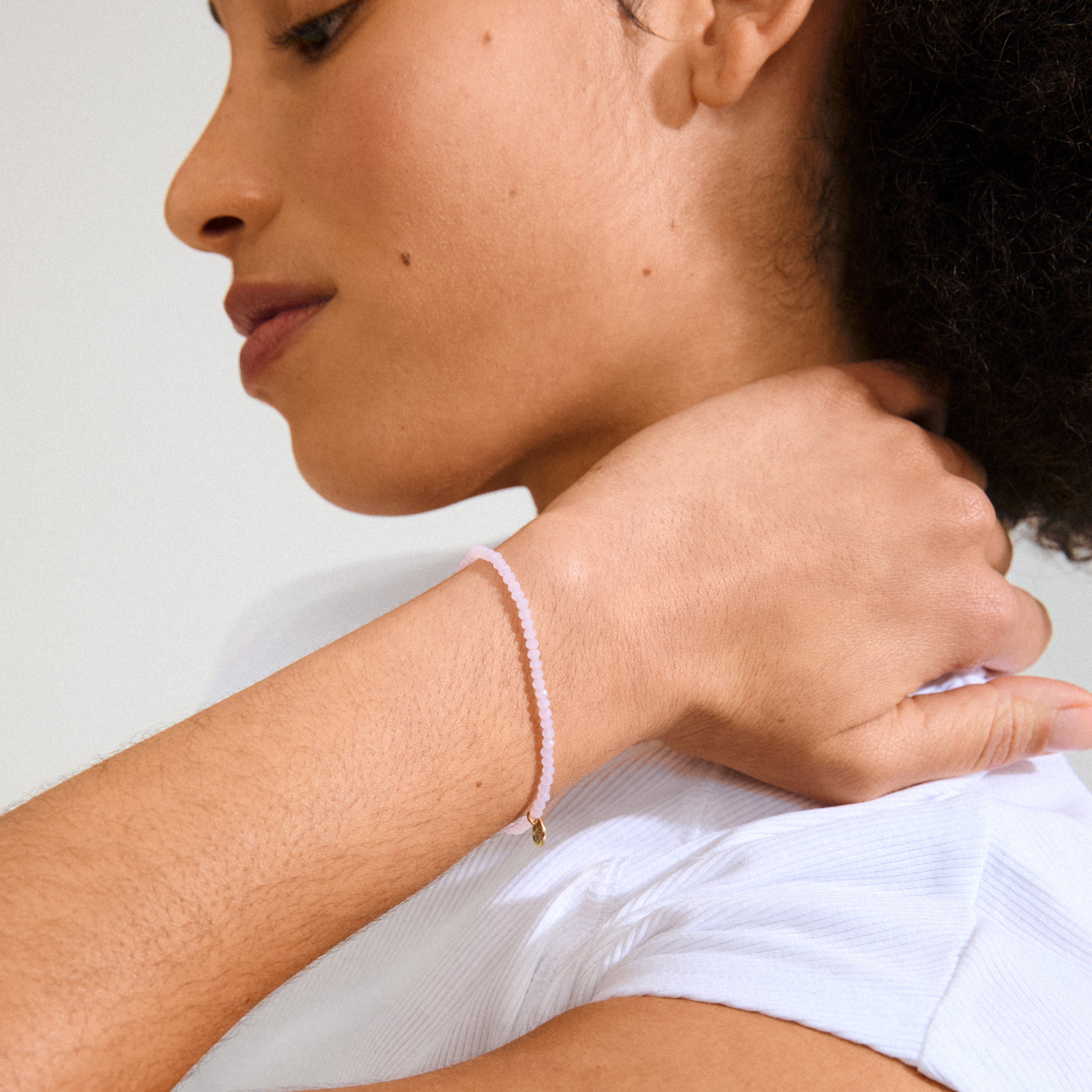 Close-up of a woman's hand showcasing the INDIE bracelet with rose faceted glass beads and gold-plated details, highlighting Pilgrim's Scandinavian-inspired design.