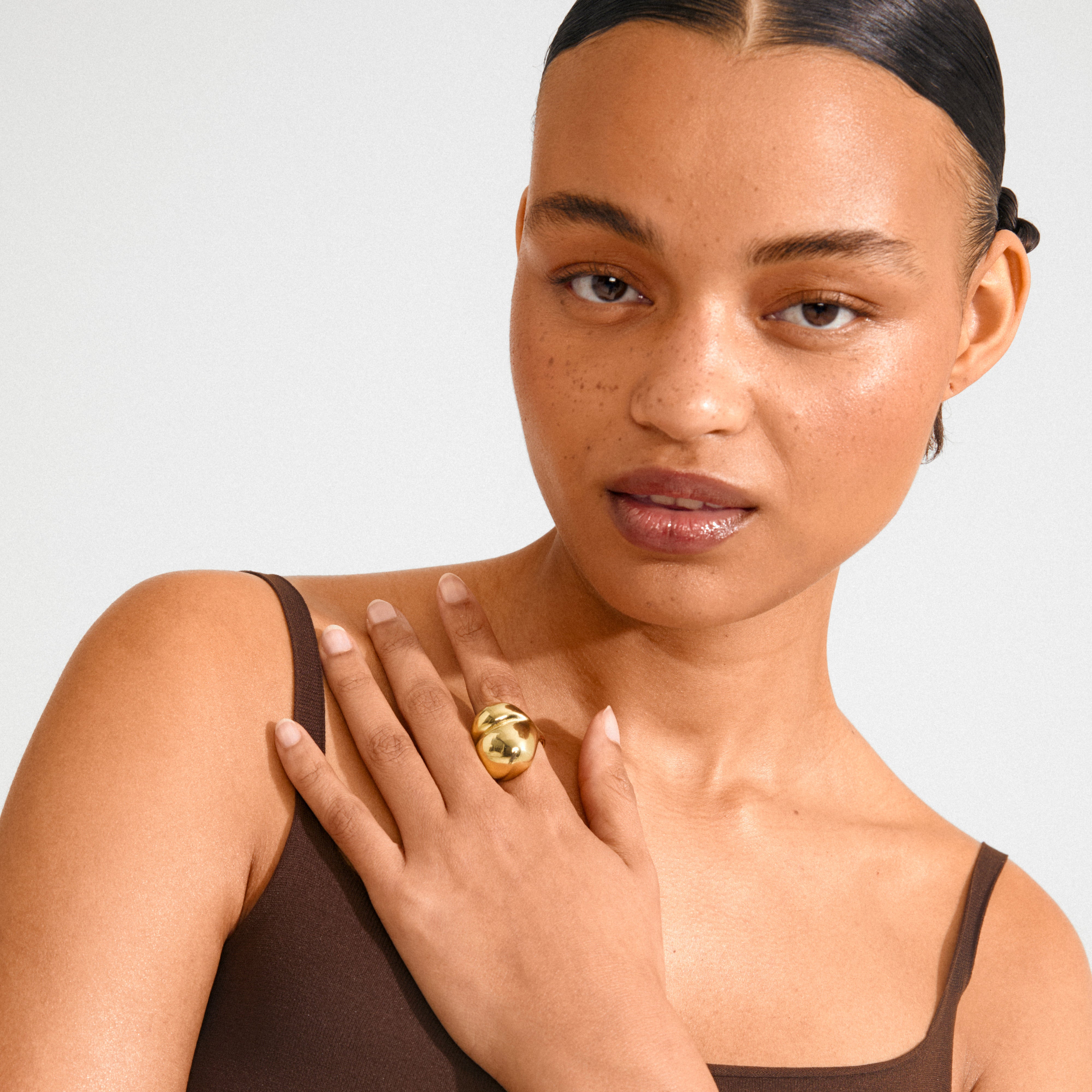 Woman showcasing the MADDIX ring gold-plated, featuring a chunky, wavy design on her hand, emphasizing its statement appeal and artistic elegance.