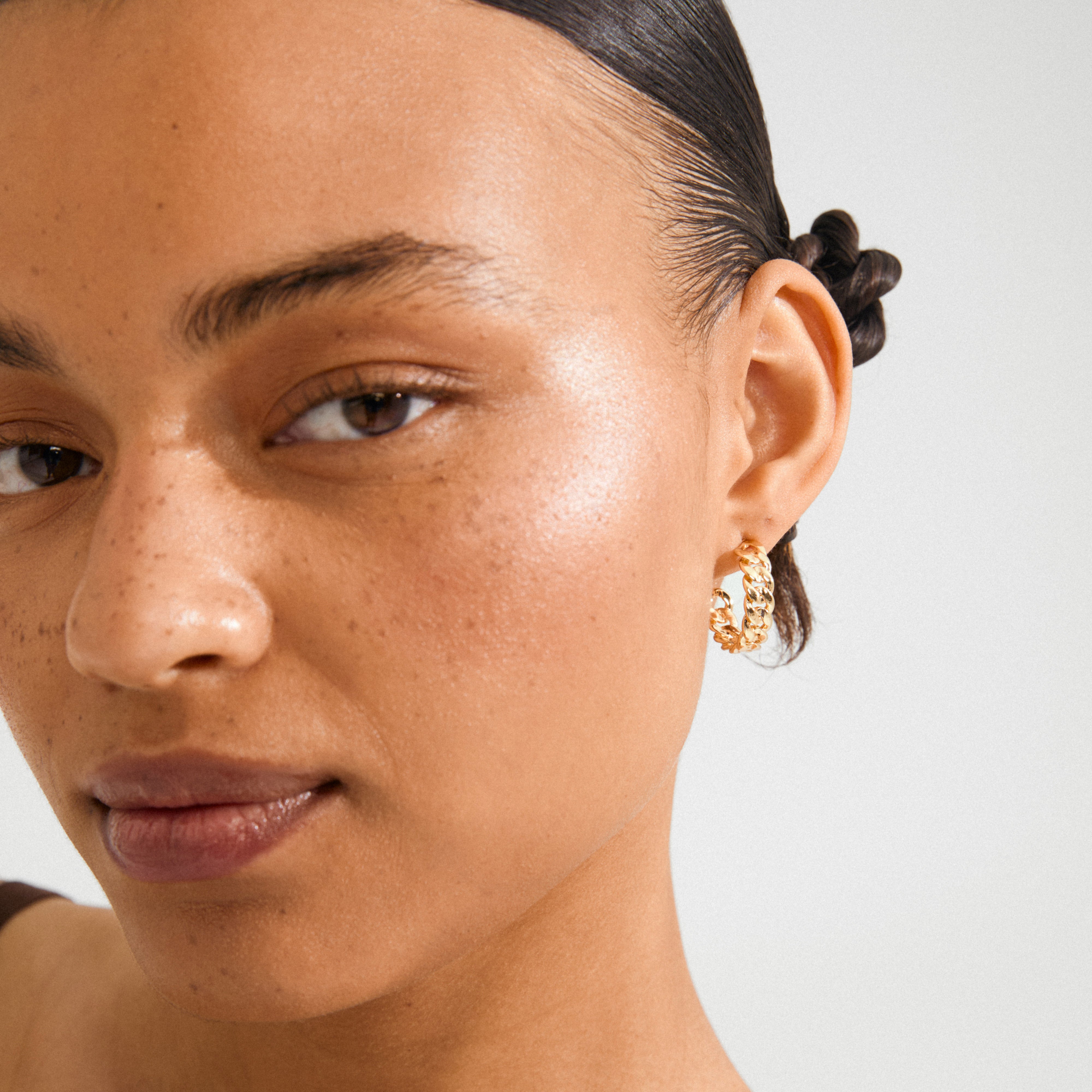 MAYER earrings gold-plated on a young woman with slicked-back hair, showcasing edgy, chunky chain-link hoops for a chic, timeless look.