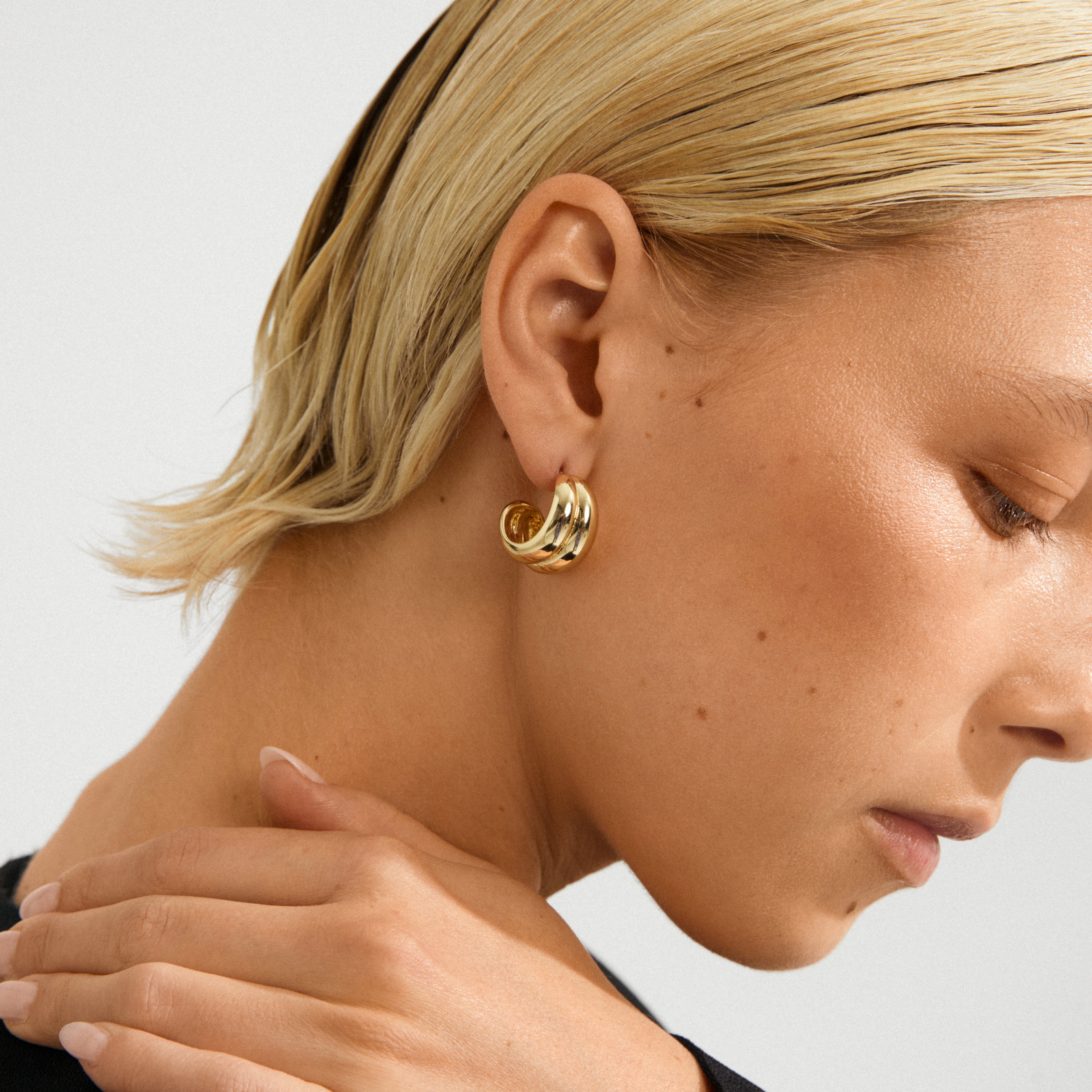 Profile view of a person wearing MIKO gold-plated, chunky double-hoop earrings, highlighting their sleek design and minimalist, modern appeal.