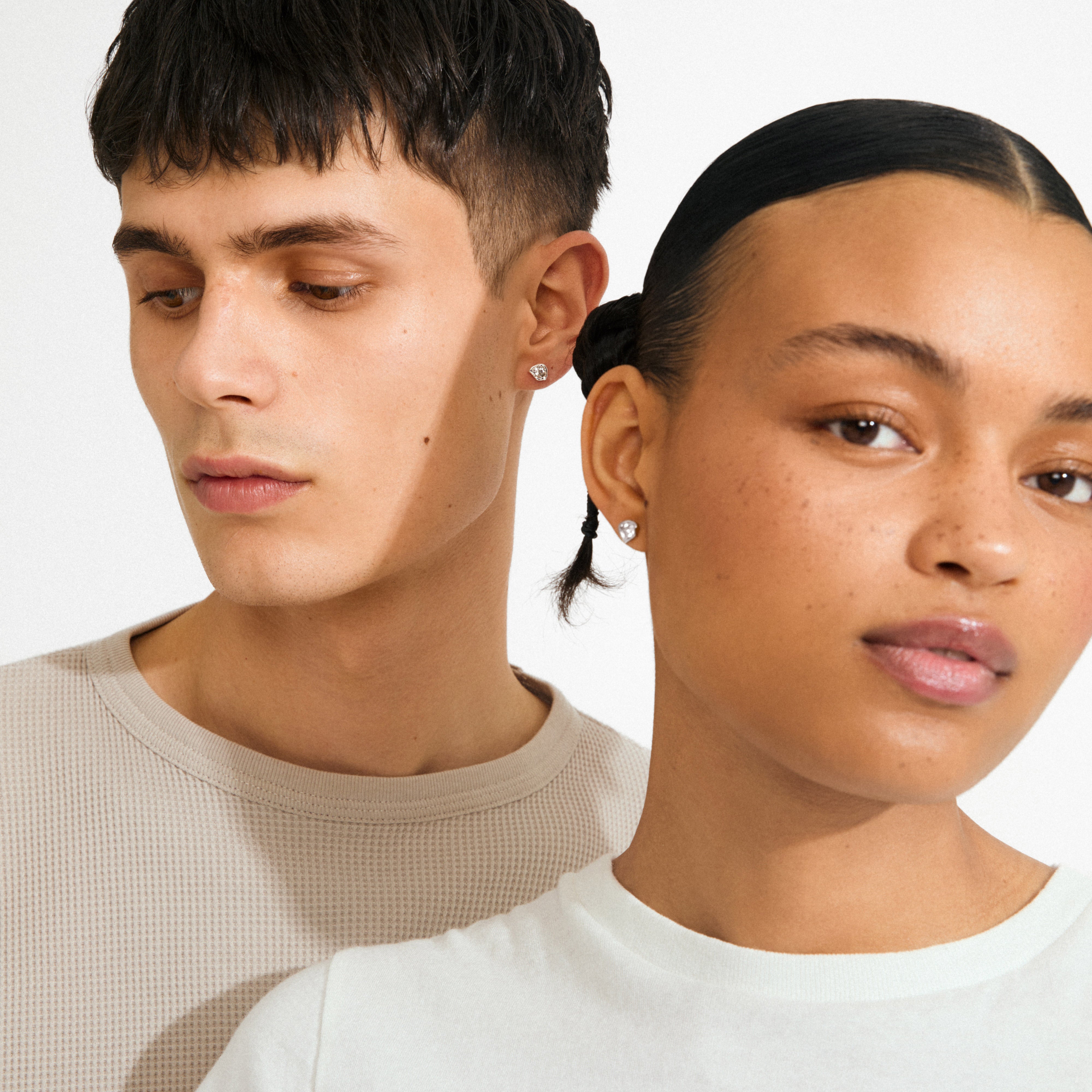 Young man and woman wearing KOTA earrings silver-plated by Pilgrim, featuring nature-inspired settings with sparkling Preciosa crystals for a subtle, stylish look.