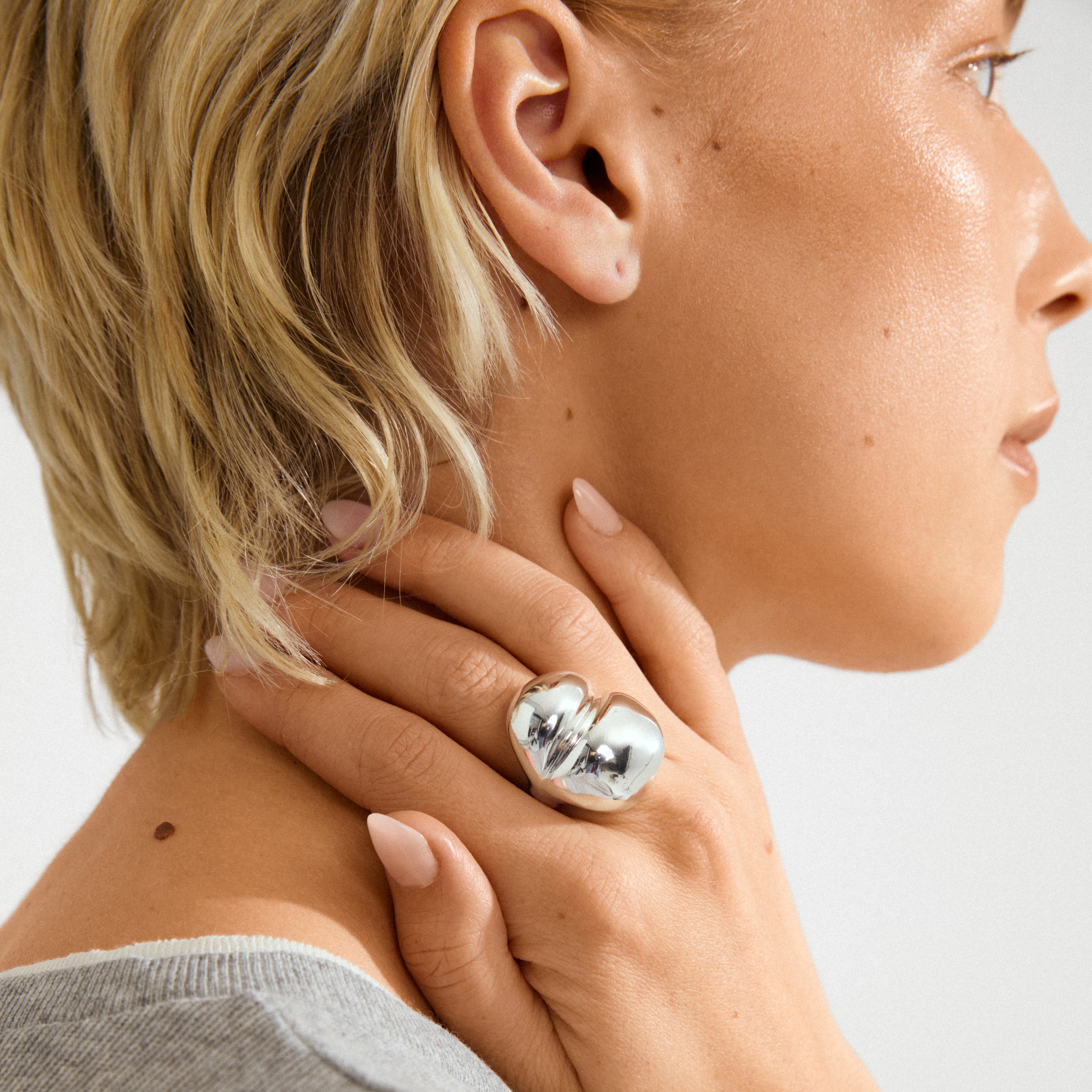 Side profile showing the MADDIX ring, a chunky, silver-plated heart-shaped statement piece by Pilgrim, resting on a neck, highlighting its bold, sculptural design.