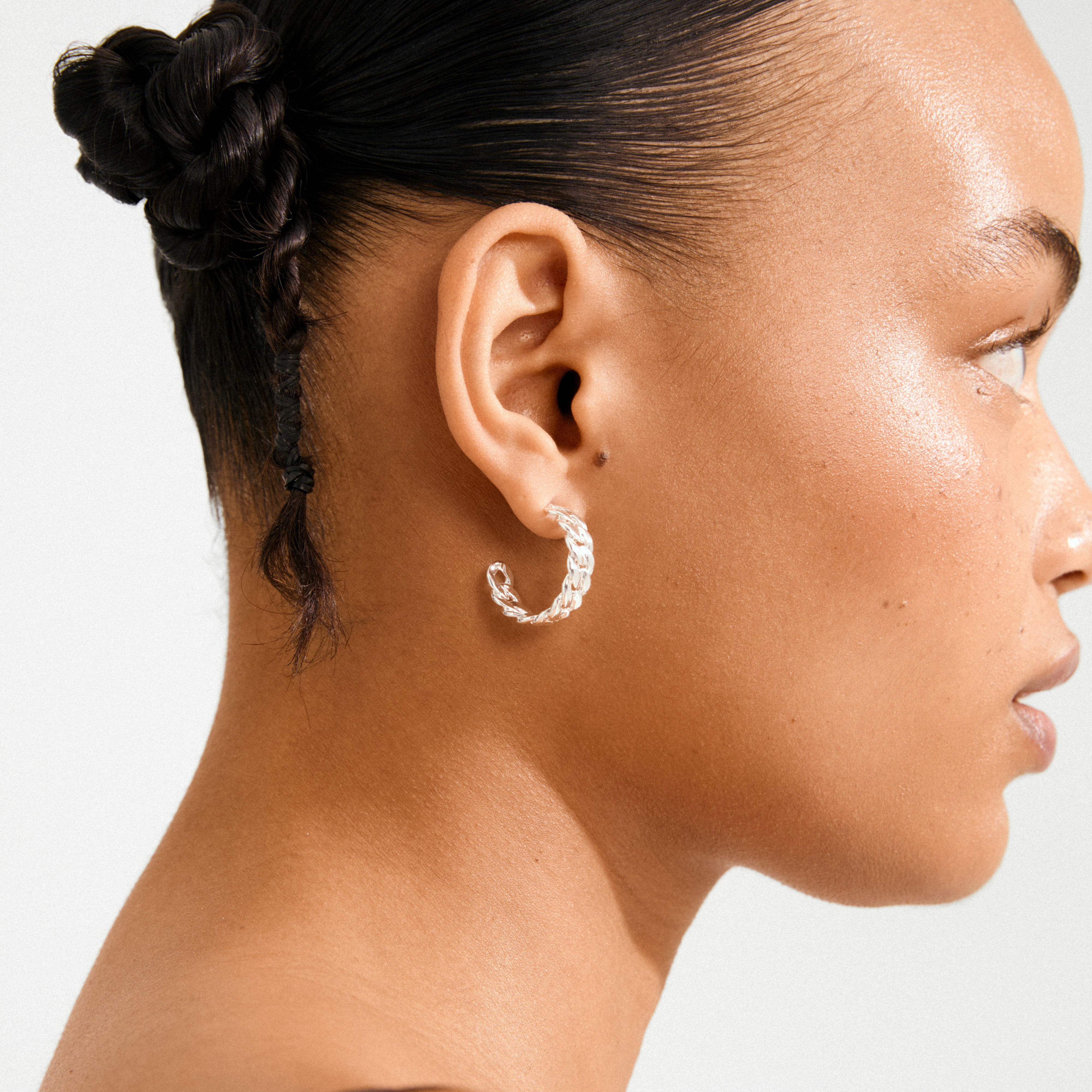 Side profile featuring a braided bun and MAYER silver-plated twisted-link hoop earring, highlighting its classic curb chain design.