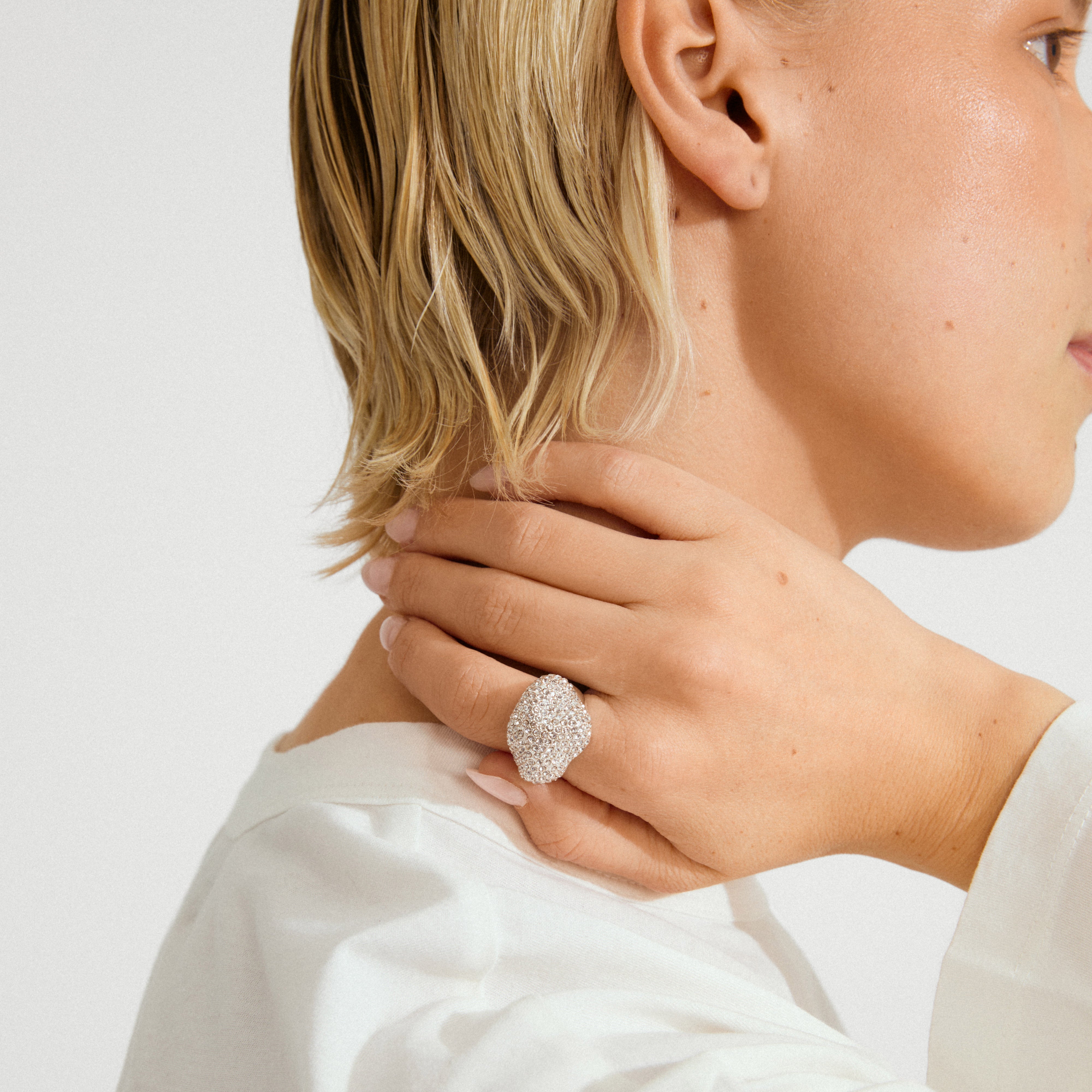 Close-up of a person wearing the silver-plated LAEL ring by Pilgrim, showcasing its wavy, pavé-style design with sparkling crystals on their hand.