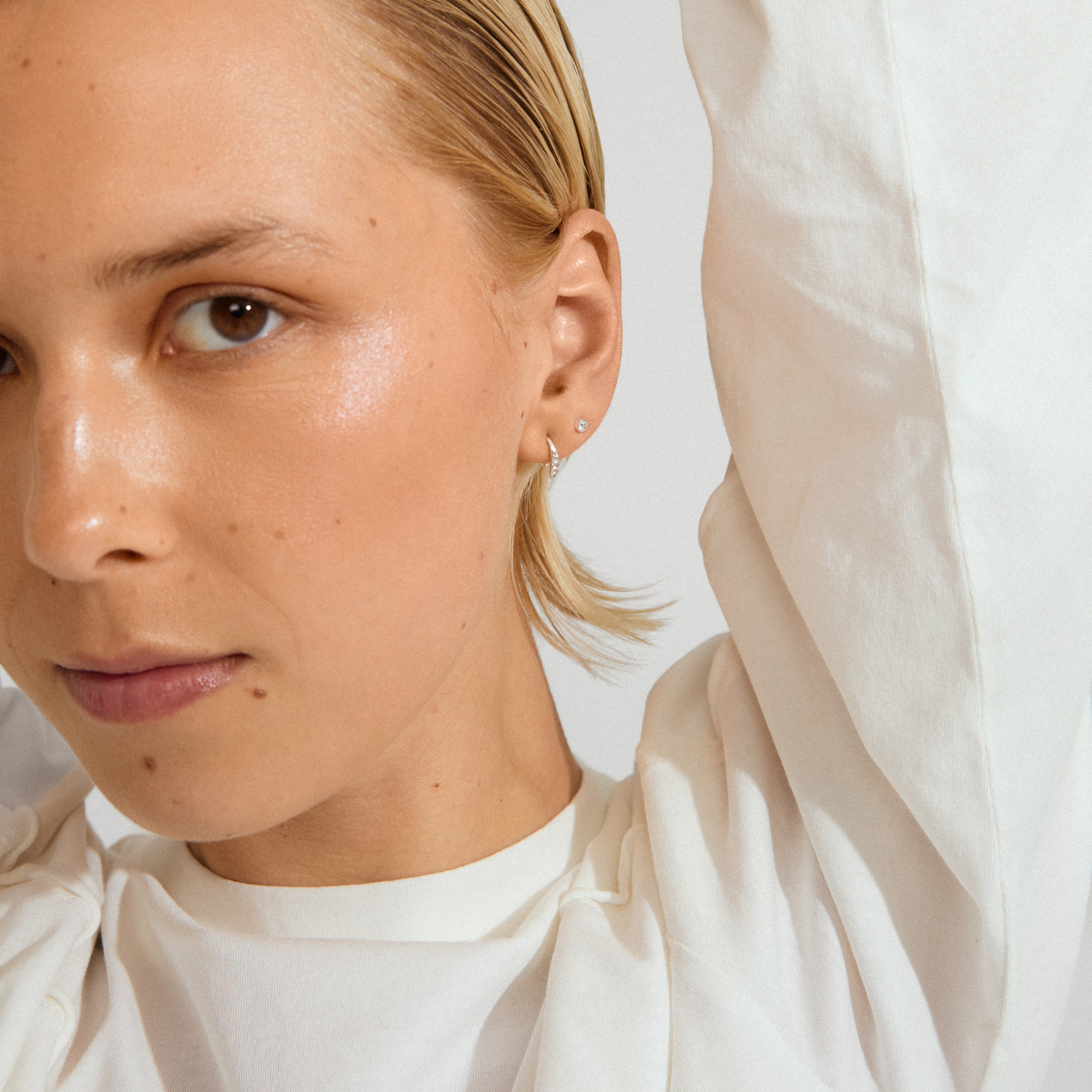 Close-up of a person wearing GIONNI silver-plated earrings, showcasing a stud and tiny hoop, embodying Pilgrim's blend of timeless and trendy design.