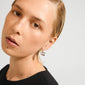 Young person wearing MIKO earrings silver-plated by Pilgrim, showcasing chunky, sculptural silver hoops against slicked-back hair and a black top.