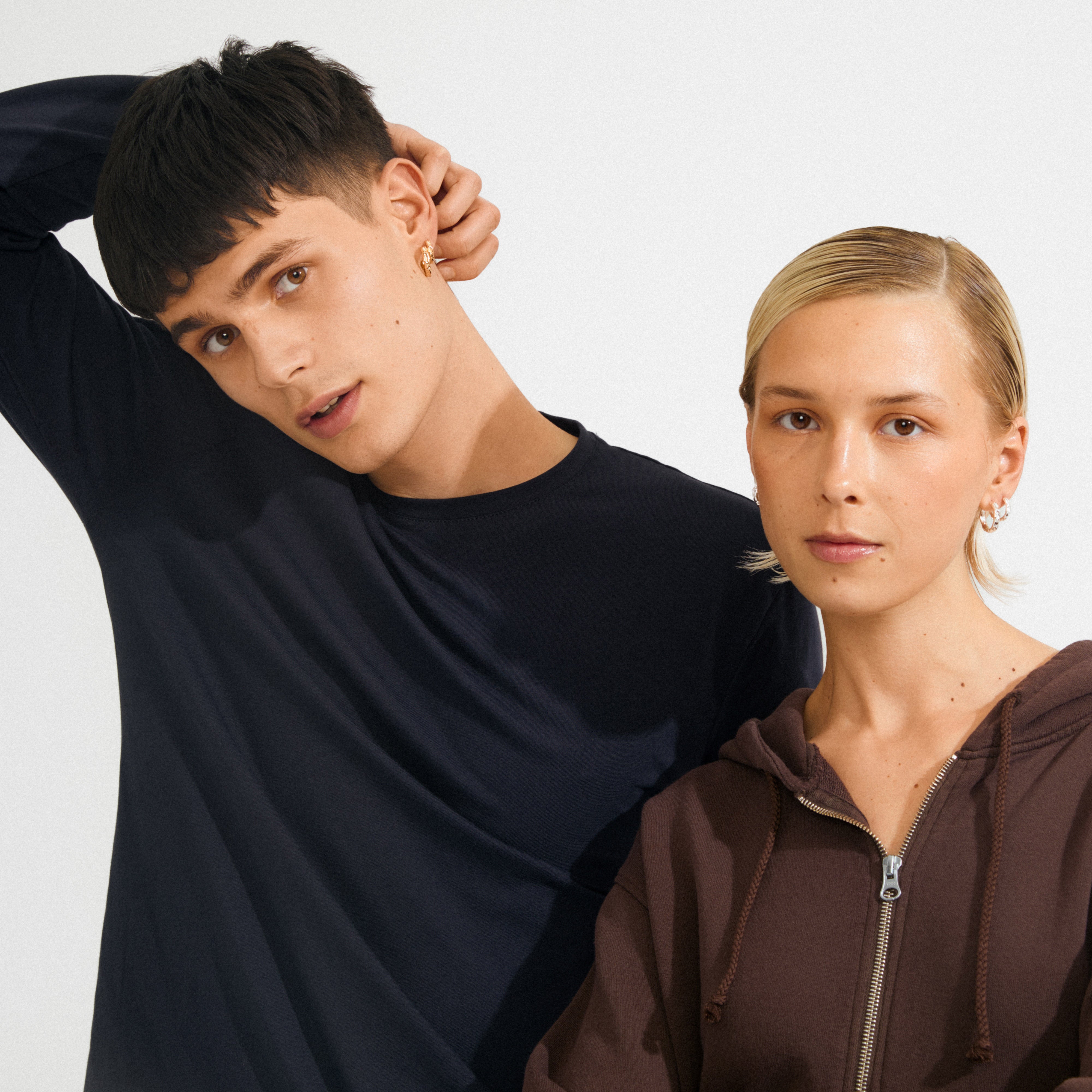 Two young adults showcase the silver-plated DARBY earrings from Pilgrim, highlighting their wavy design and versatile styling options.
