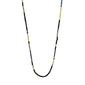 ALISON necklace by Pilgrim, featuring sleek, tube-shaped glass beads in matte black and metallic gold, laid in a U-shape on a white background.