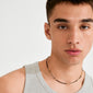 Close-up of a young man wearing the ALISON necklace by Pilgrim, featuring sleek black and gold tube-shaped beads, paired with a light gray ribbed tank top.