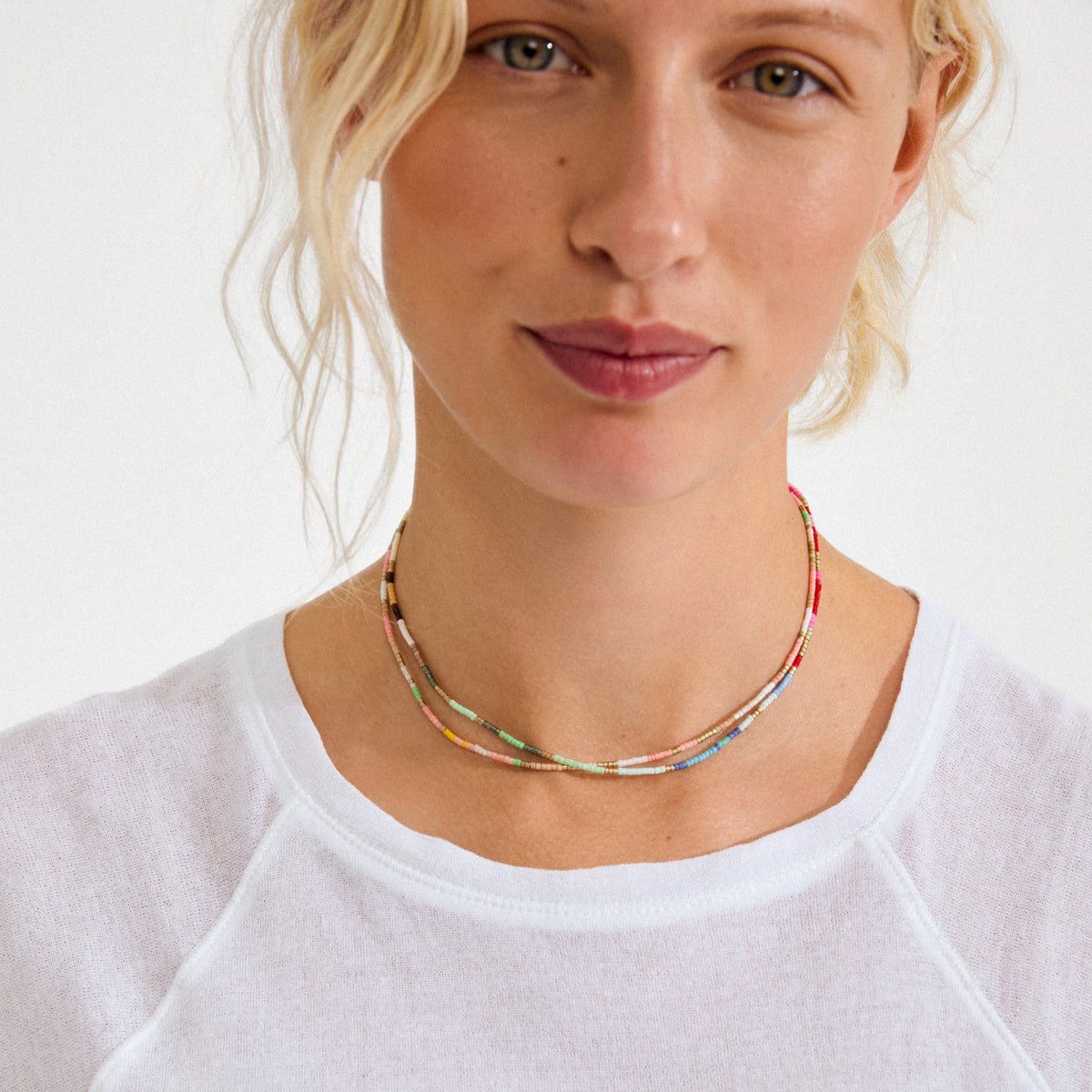 Young woman wearing Pilgrim's ALISON necklace, a multicolored, two-strand seed-bead piece, adding vibrant, playful energy to her relaxed summer look.