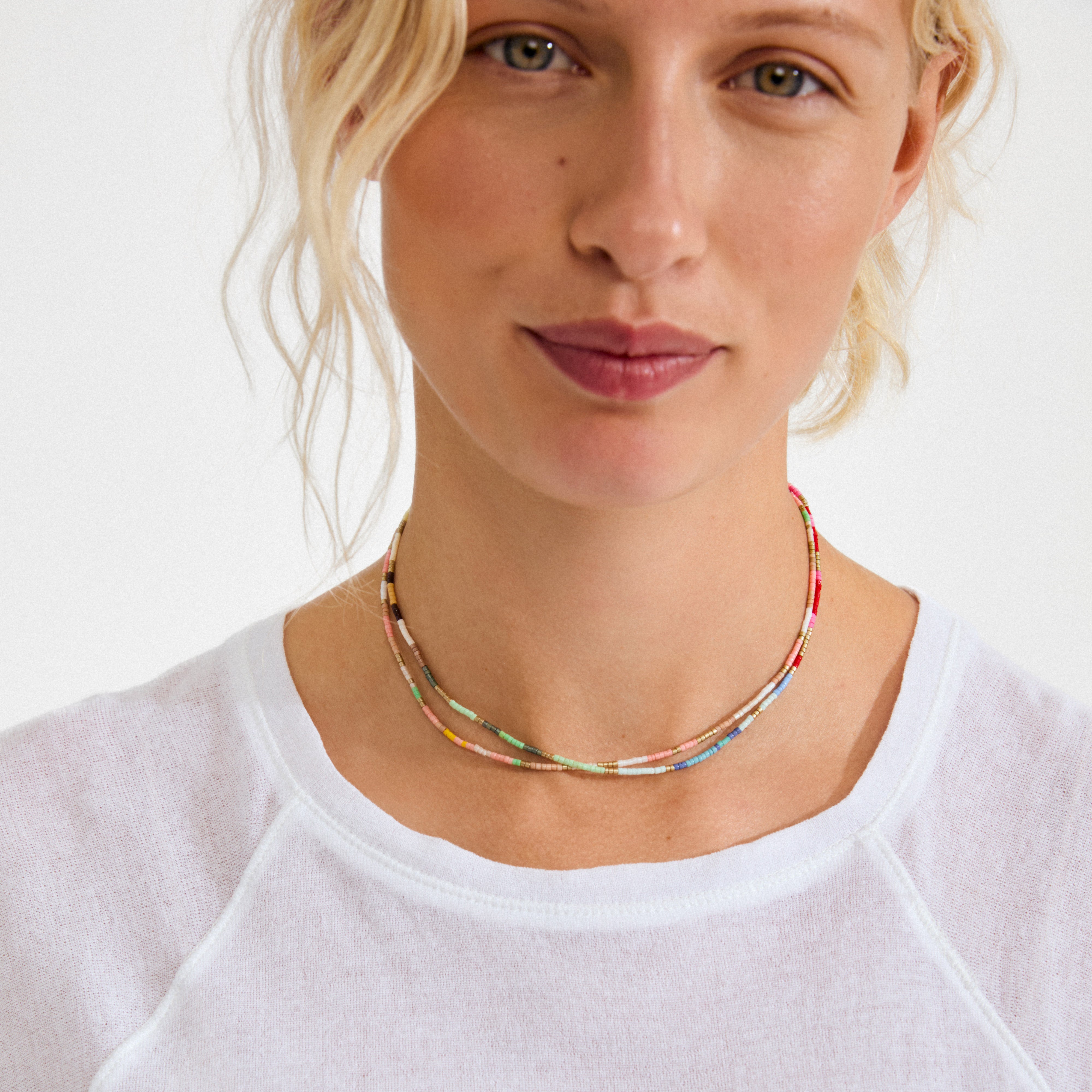 Close-up of a woman wearing the ALISON necklace multi, gold-plated by Pilgrim, featuring small, multicolored seed beads in a choker style.