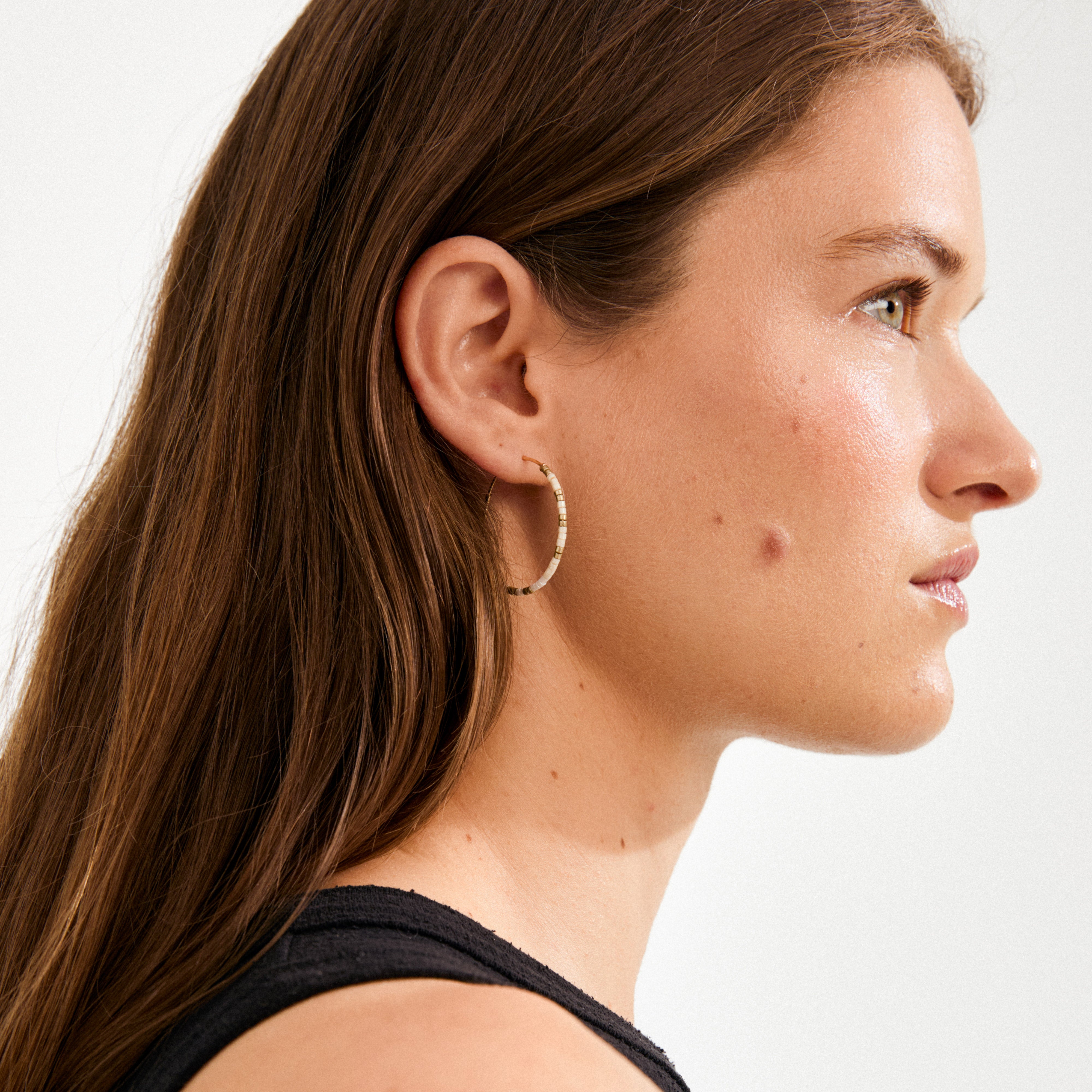Young woman wearing ALISON earrings with cream and gold beaded hoops, showcasing Pilgrim's minimalist, boho-inspired design.