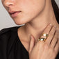 Close-up of a woman's hand adorned with the ALMA gold-plated ring, featuring a double-twined design with contrasting shiny and matte finishes, showcasing Pilgrim's craftsmanship.
